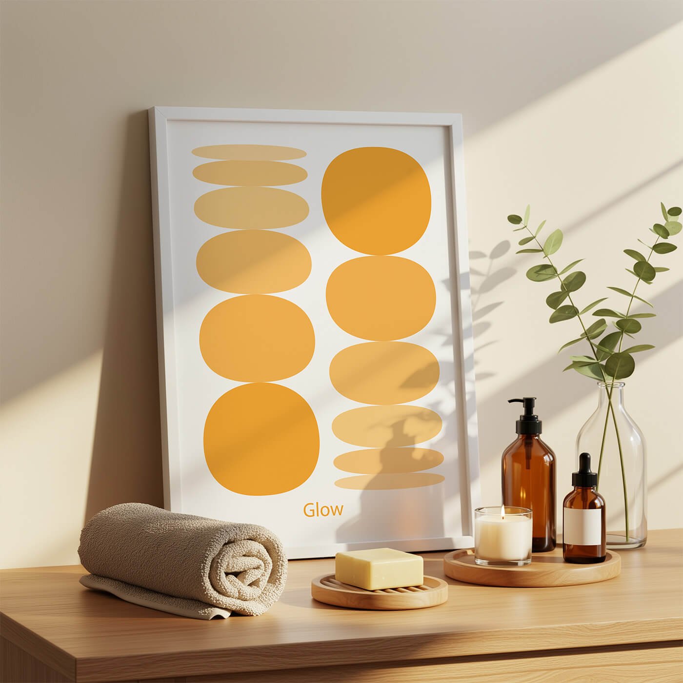 Framed abstract art print titled Glow, displaying vibrant yellow and orange balancing stone graphics on a sunny table display