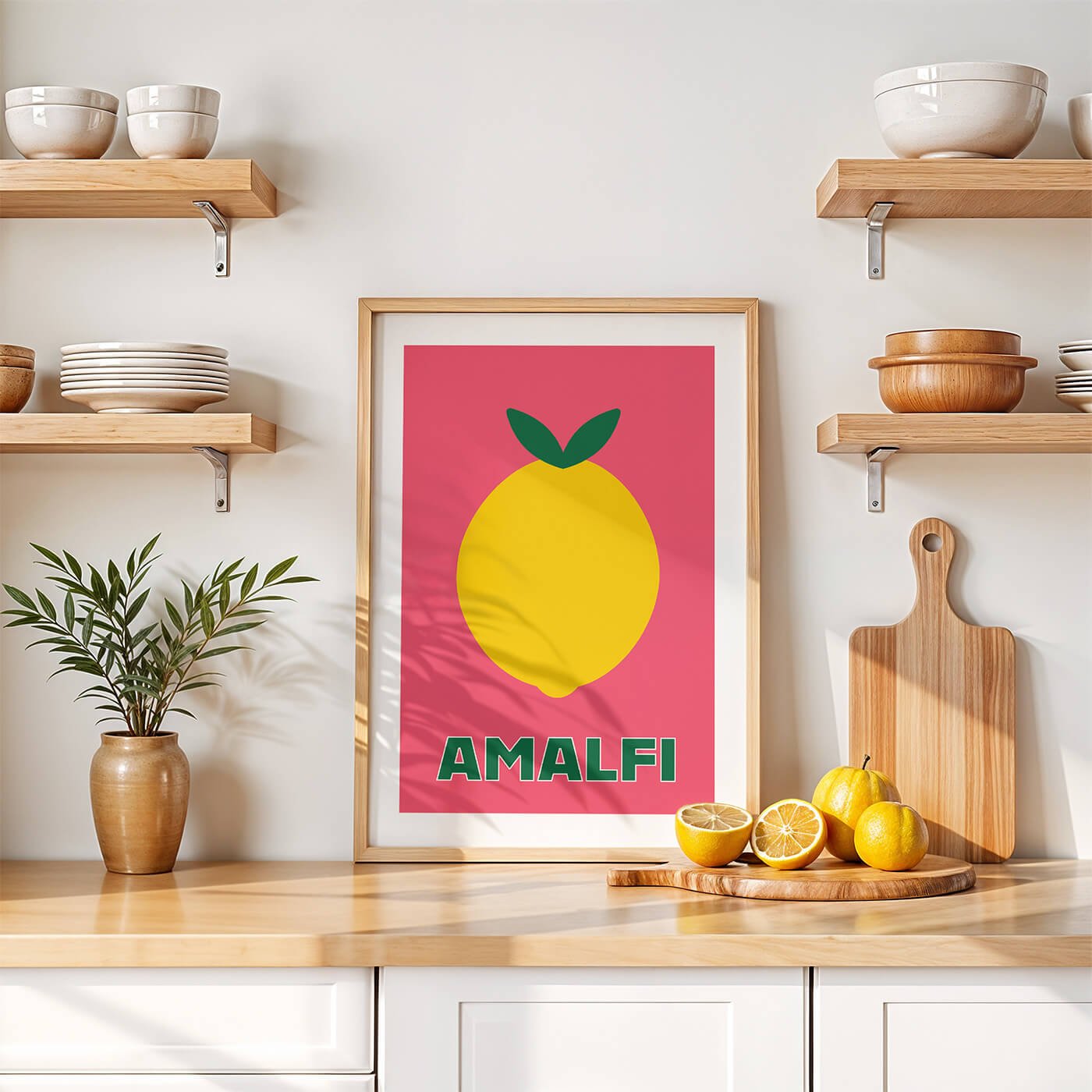 A framed vibrant pink Amalfi lemon art print showcased on a white marble kitchen worktop in a bright modern home