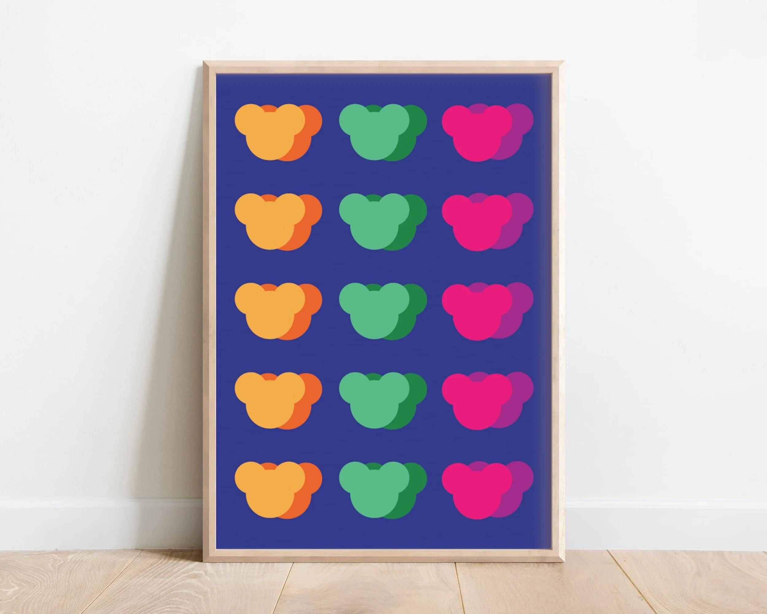 Playful childrens print of multiple colourful teddy bear faces with blue background displayed in wooden frame against while modern wall