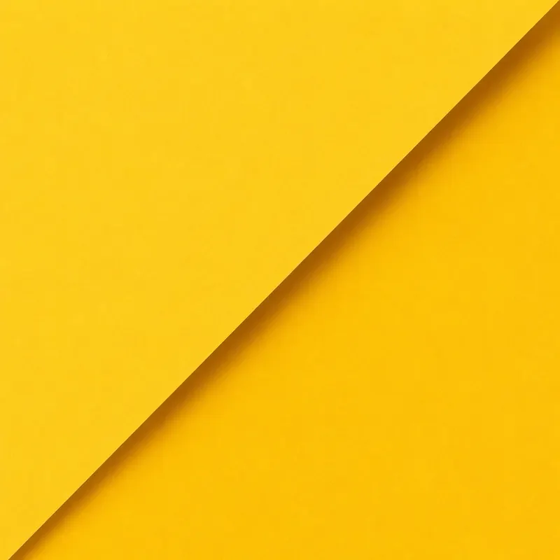 Close-up of yellow paper with a diagonal cut, creating a shadowed edge.