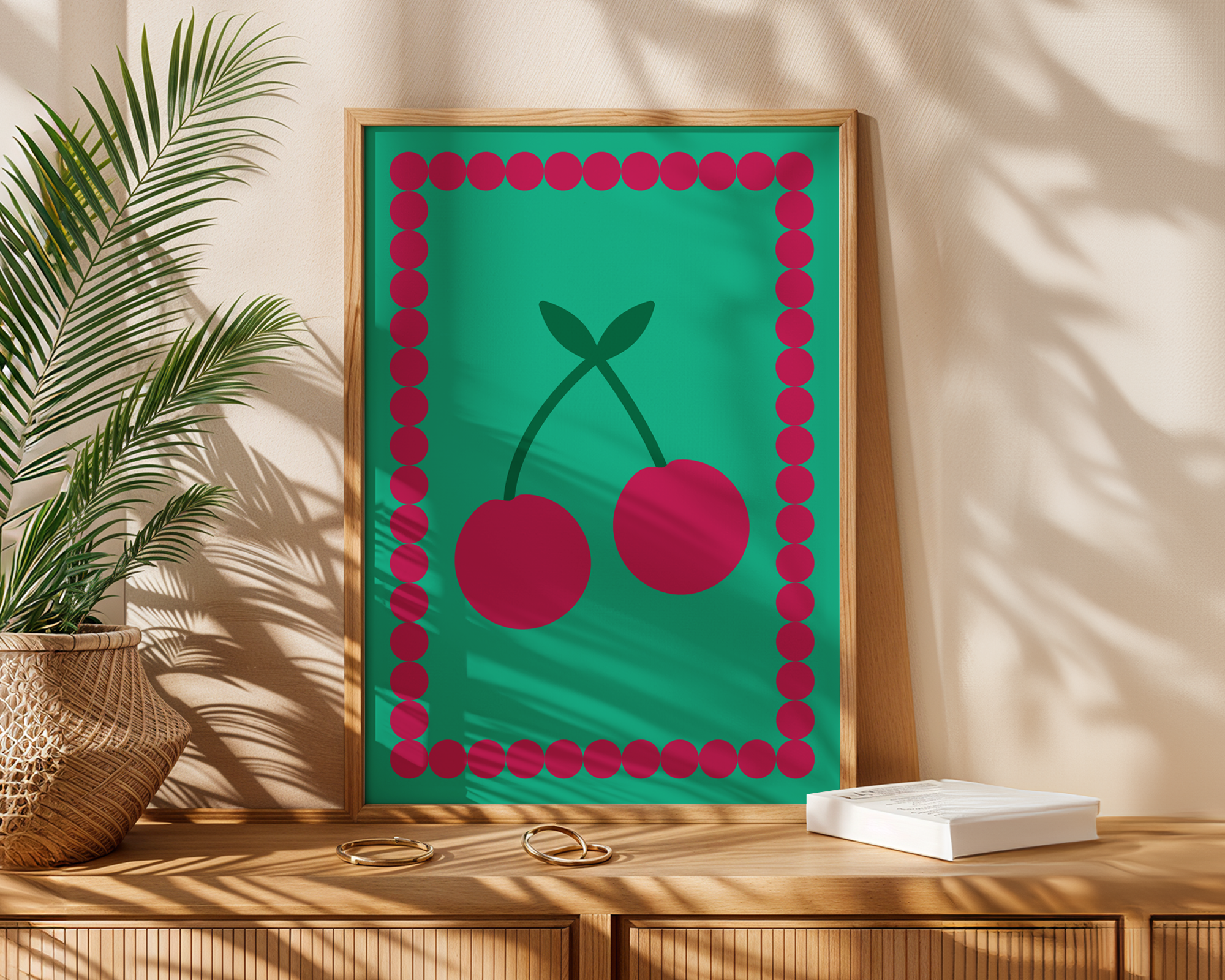 colourful poster of cherries in frame on table next to plant
