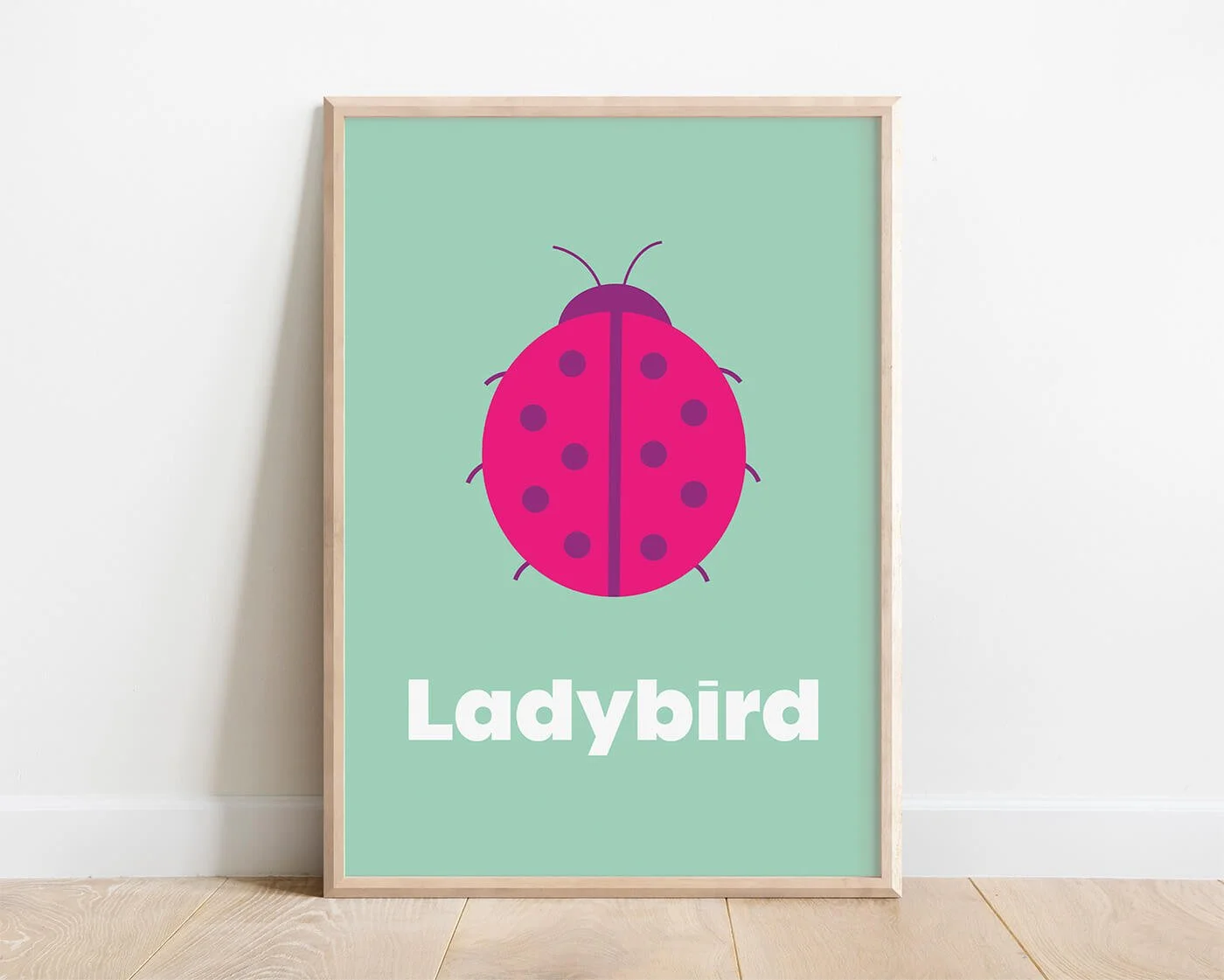 Ladybird Learning Print in a modern oak frame displayed on a white interior wall. Contemporary ladybird wall art featuring a colourful ladybird illustration and the word "Ladybird"