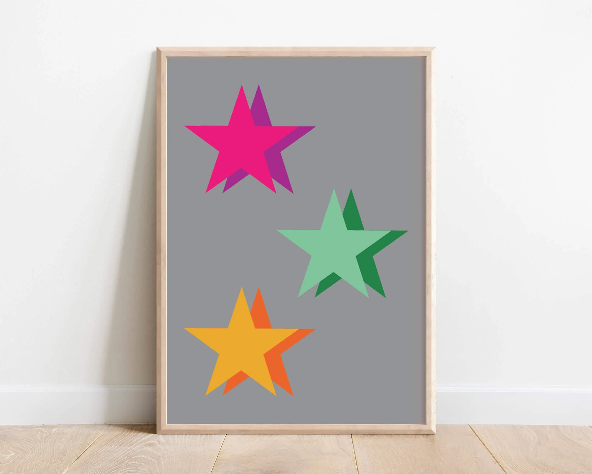 Framed colourful star print featuring three brightly coloured stars in pink, yellow, and green on a slate grey background