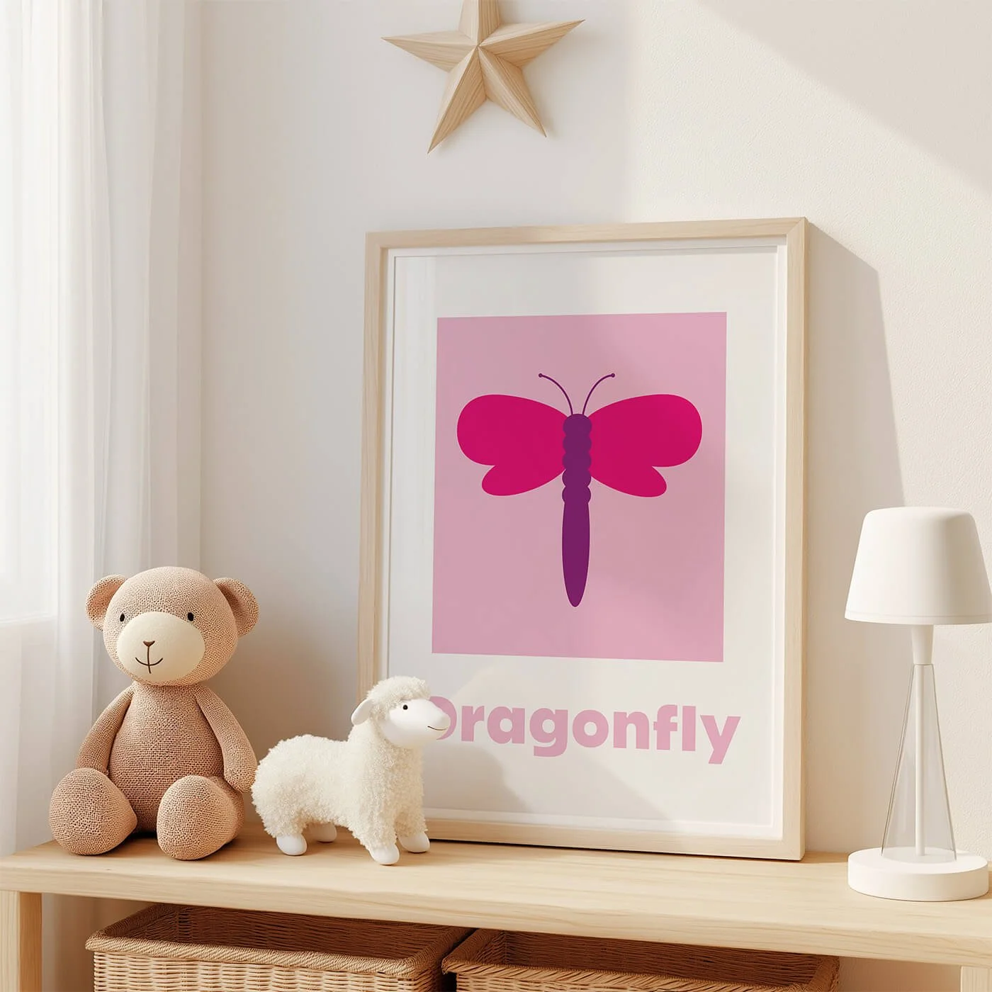 Dragonfly Learning Print displayed in a modern oak frame on a shelf in a contemporary children's bedroom with two soft toys. Colourful dragonfly wall art on a pink background.