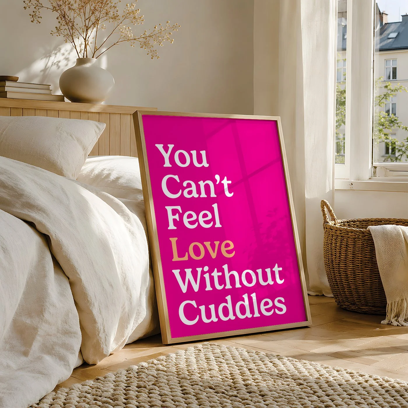 pink love typography print displayed in frame resting against in bed in neutral decor bedroom