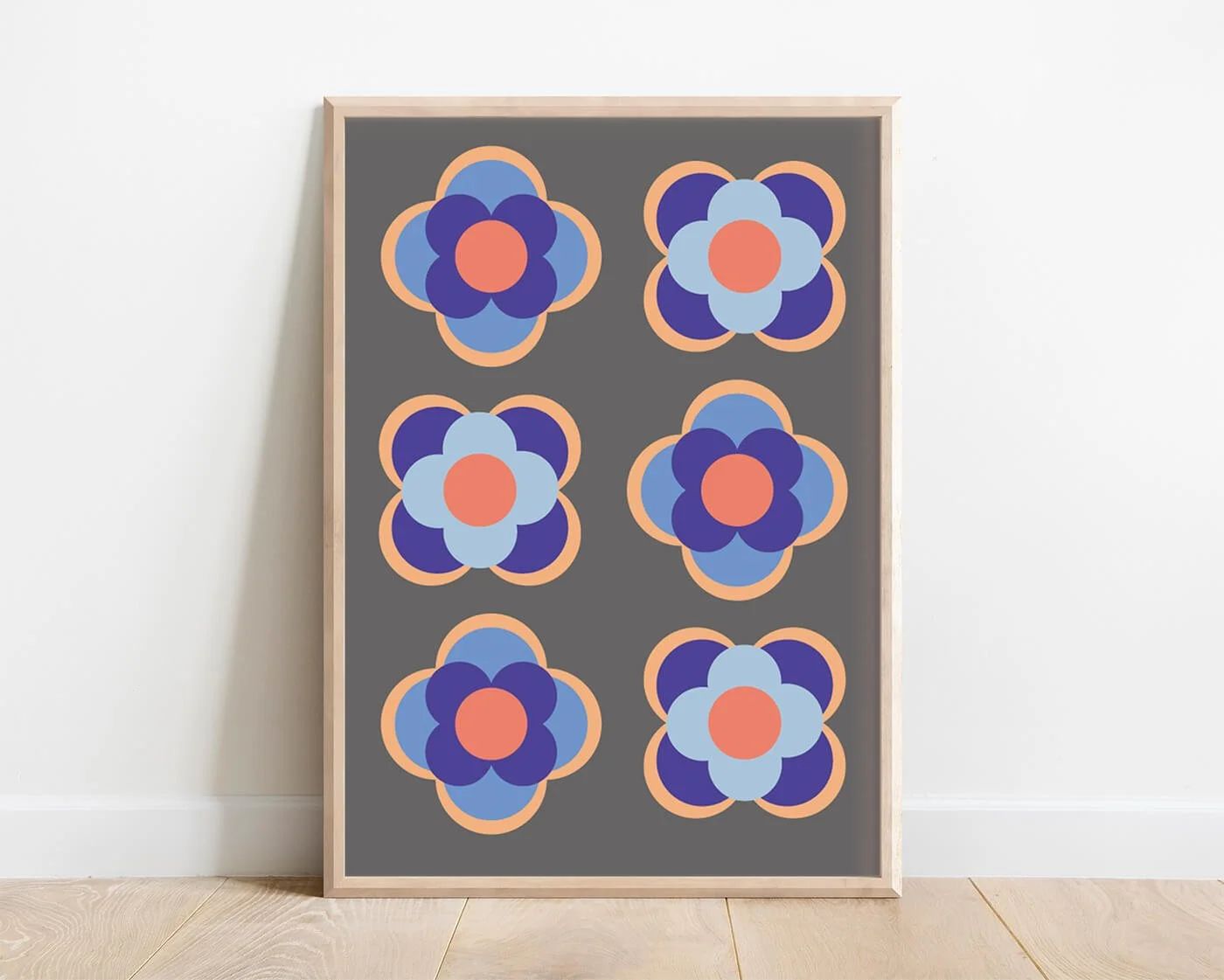 Premium mid-century modern geometric floral print with blue and orange tones, framed in light wood and leaning against a white wall