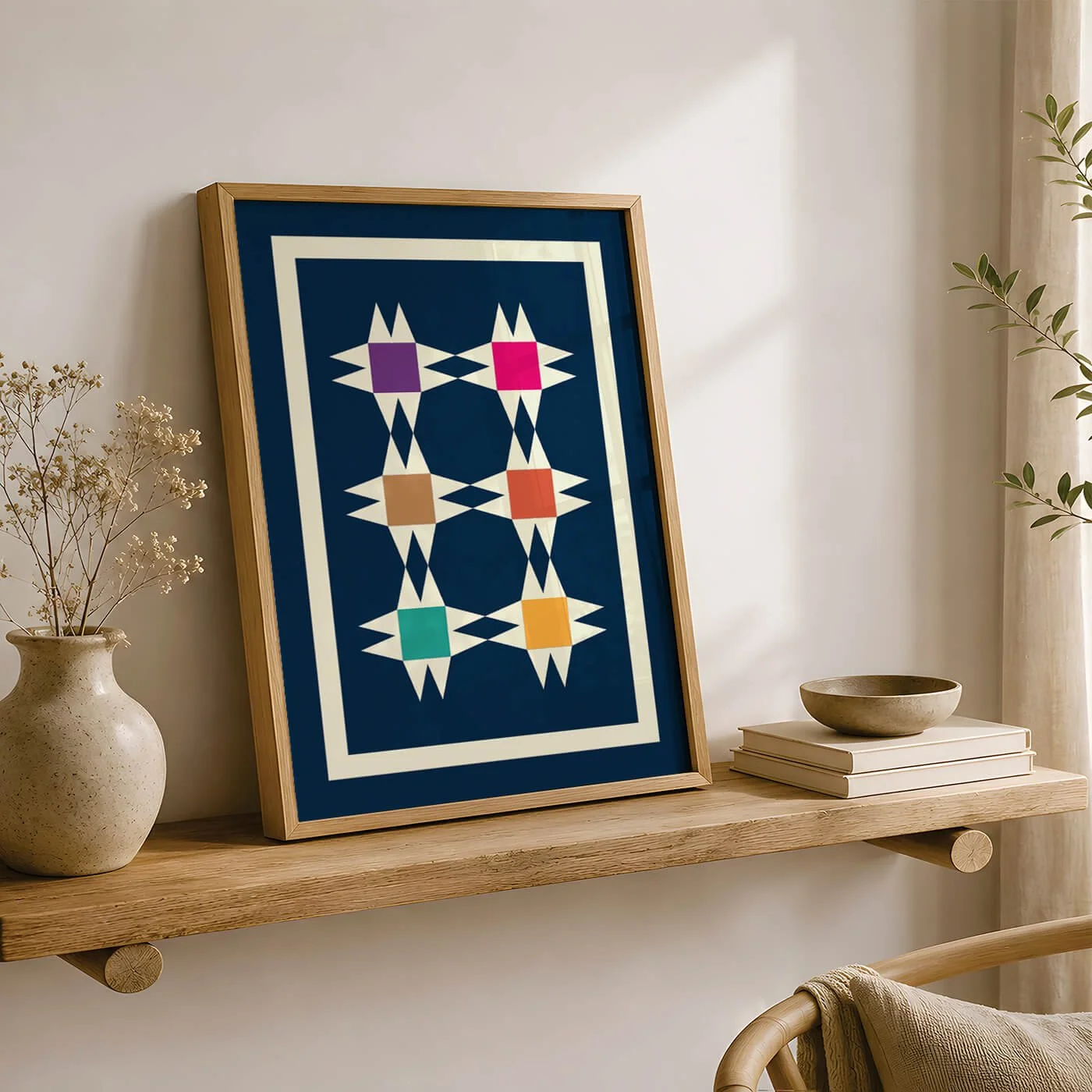 Framed colourful geometric tile artwork displayed on a wooden wall shelf with a vase, bowl, books, and plants.