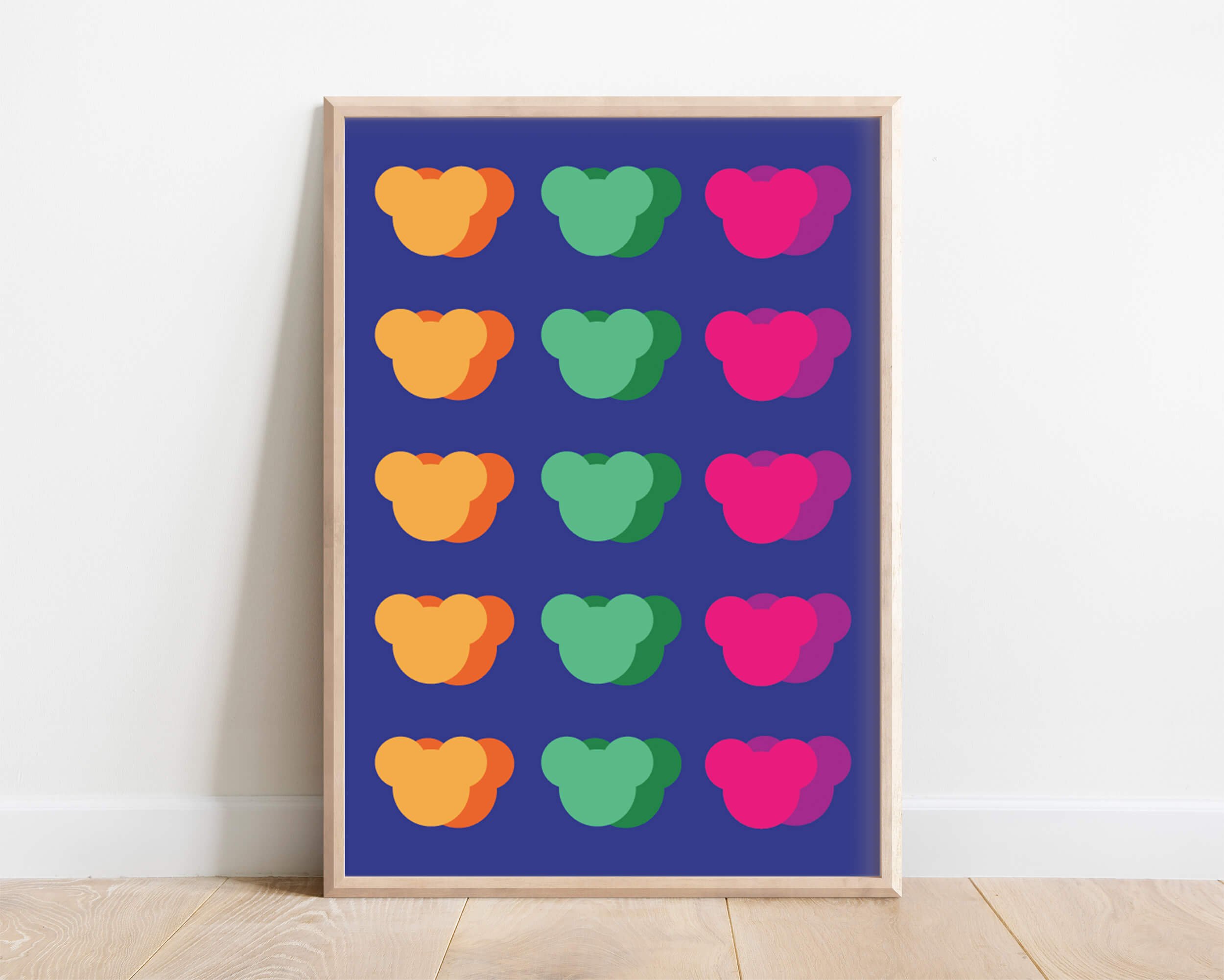Playful childrens print of multiple colourful teddy bear faces with blue background displayed in wooden frame against while modern wall