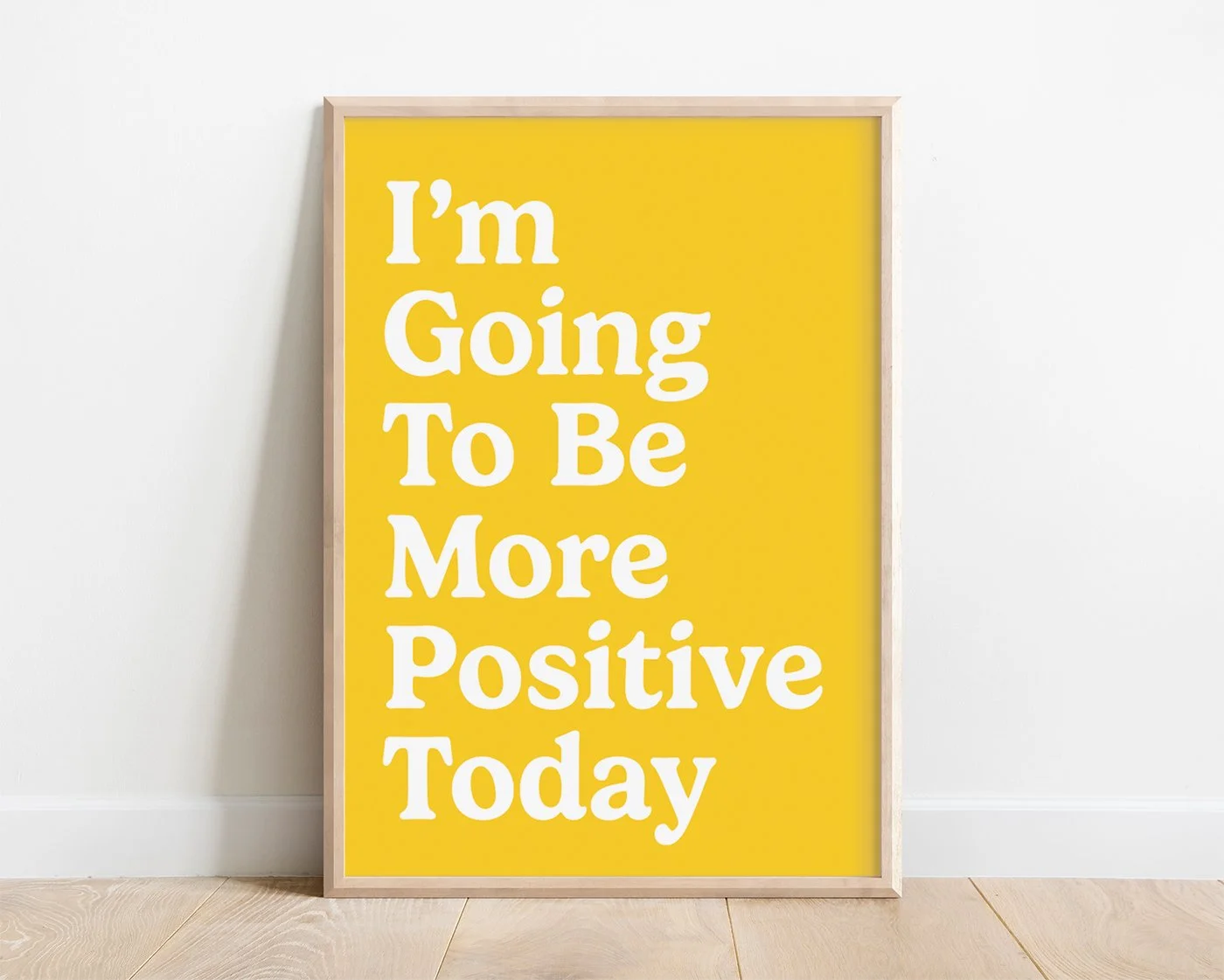 Yellow positivity typography print in a light wooden frame, featuring the quote “I’m Going To Be More Positive Today” in bold white lettering.