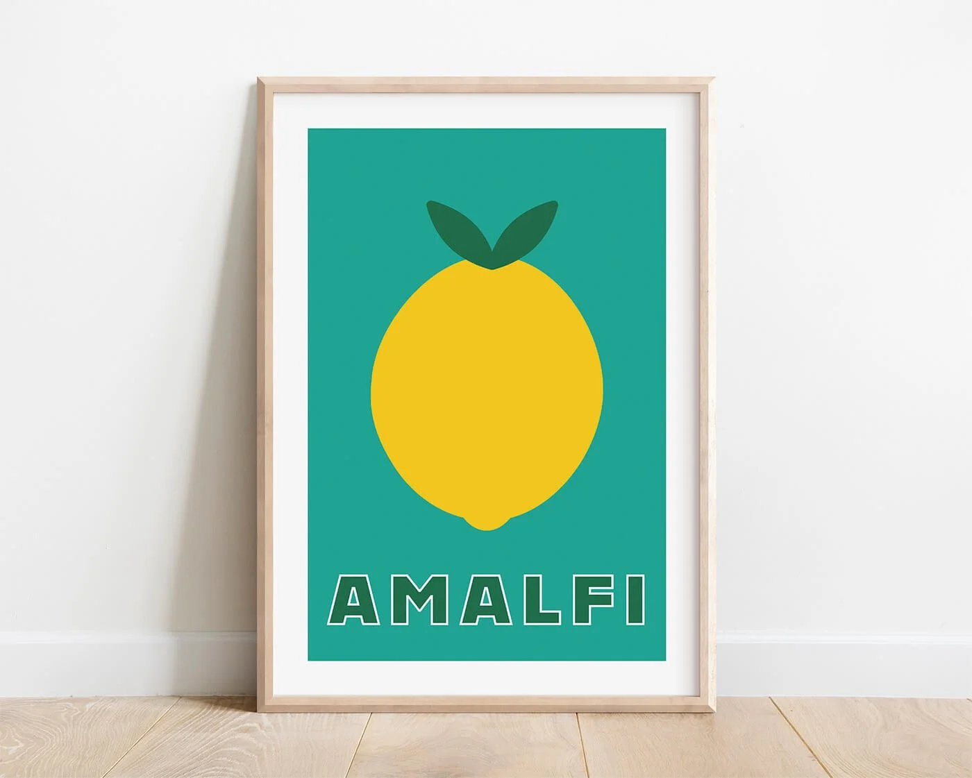 A bold Italian food art print of a yellow lemon on a teal green background, displayed in a wooden poster frame on a blank white dining room wall.