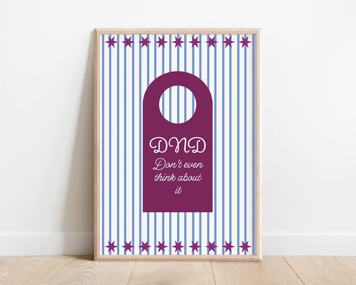 Burgundy Do Not Disturb Print in a modern wooden frame displayed against a minimalist white wall.