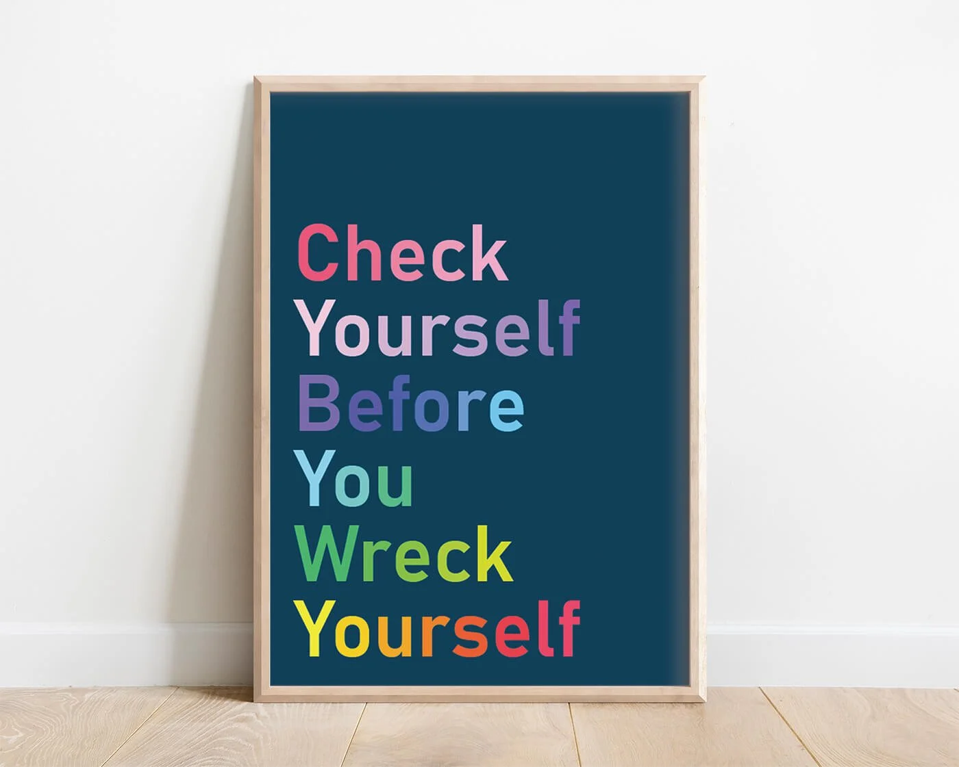 Rainbow Check Yourself print with colourful bold typography on a blue background in a wooden frame