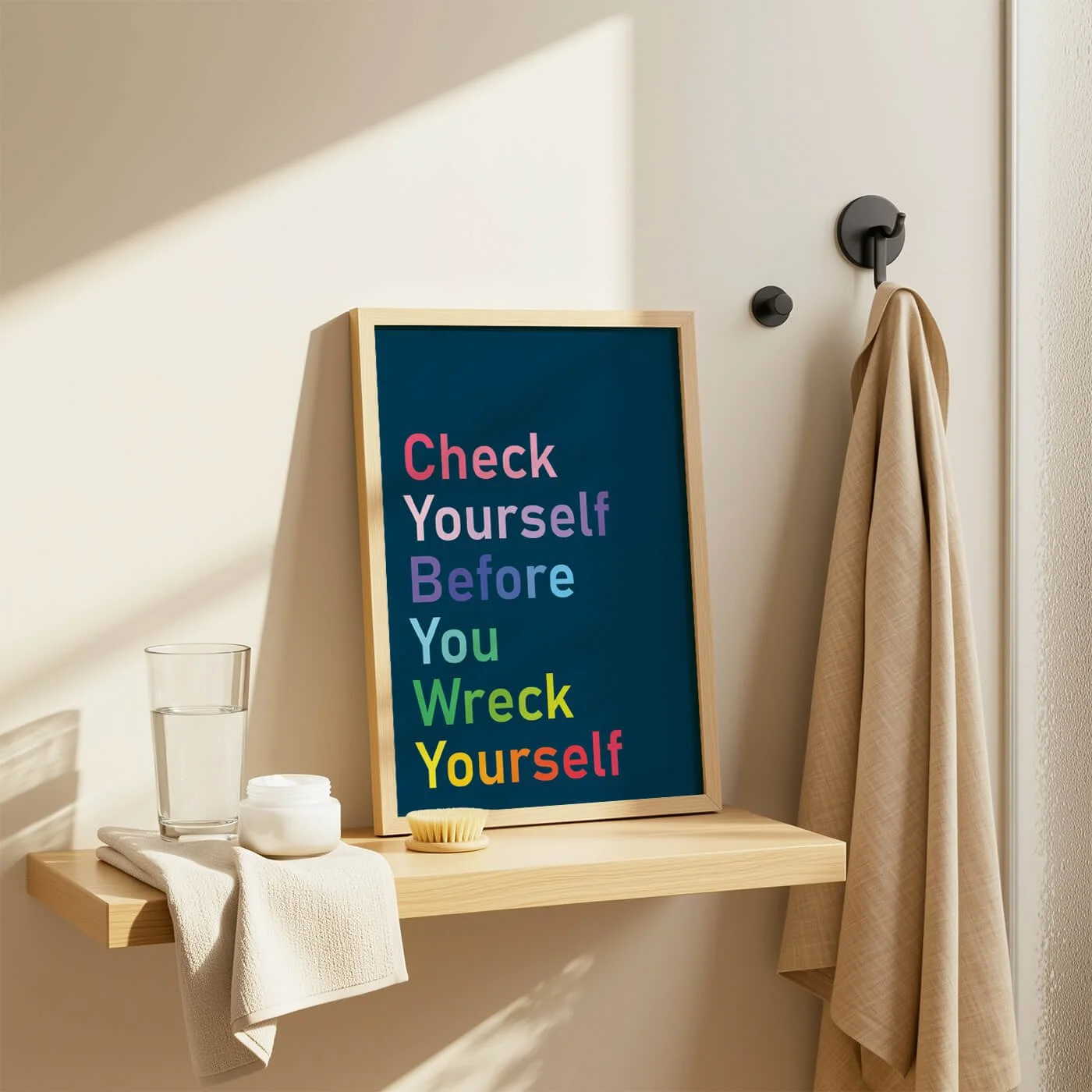 Rainbow Check Yourself print in a wooden frame displayed on a bathroom shelf