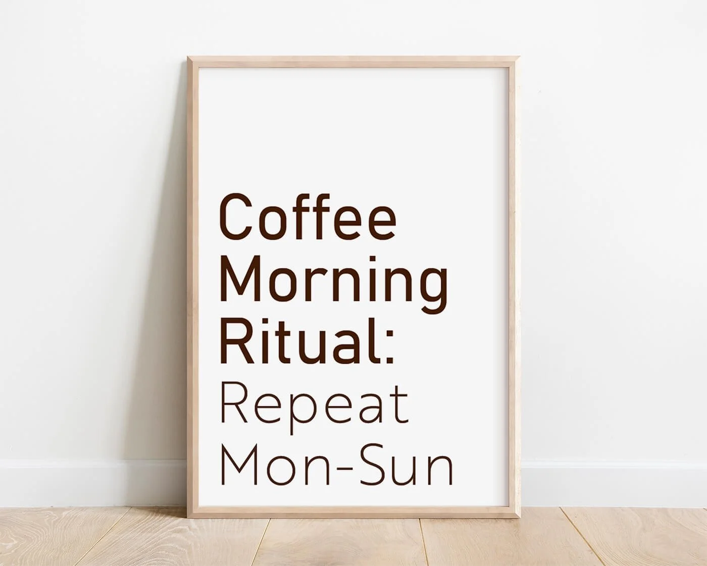 Framed typography print with the words 'Coffee Morning Ritual: Repeat Mon-Sunday. displayed on a white interior background