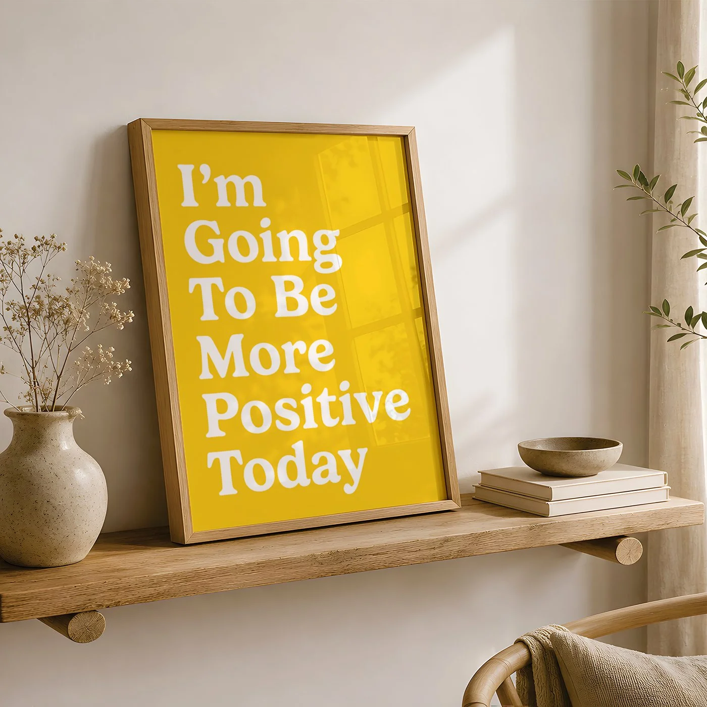 Vibrant yellow positive quote print displayed in a wooden frame on a shelf, styled with neutral ceramics and natural decor.