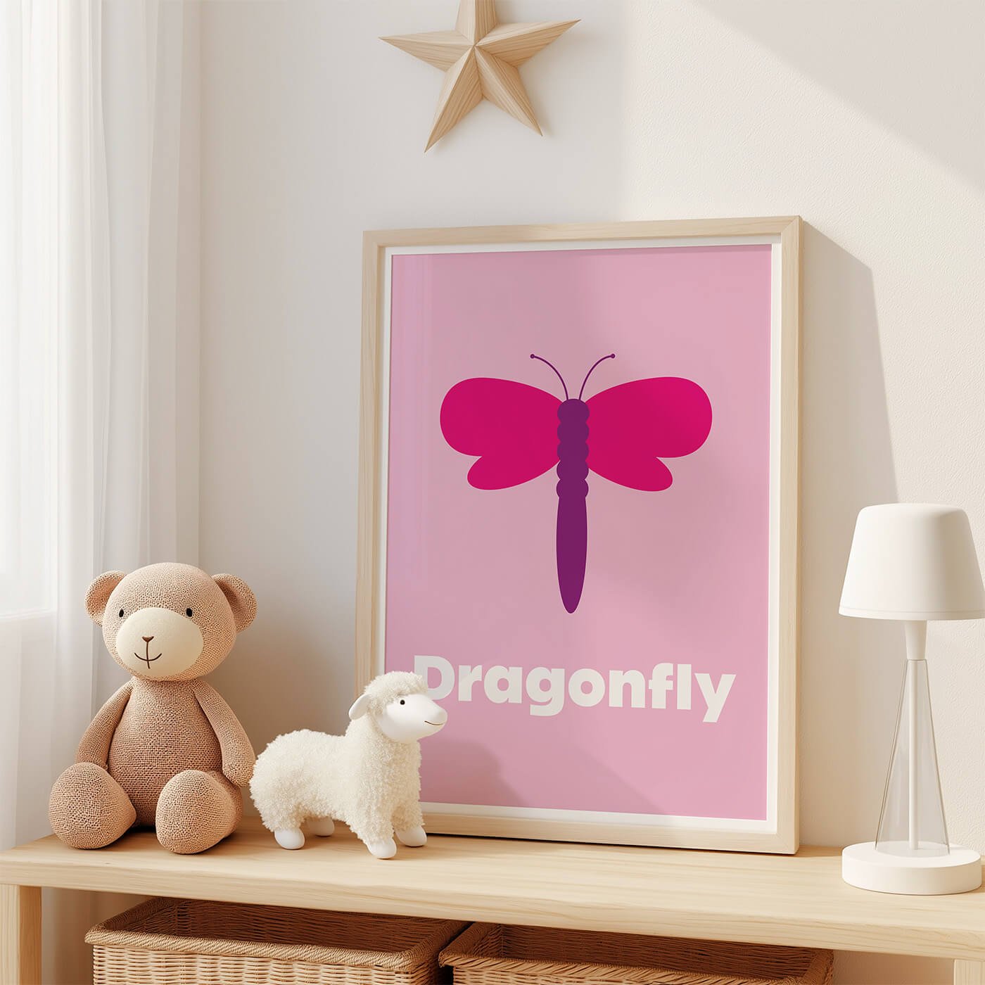 Dragonfly Learning Print displayed in a modern oak frame on a shelf in a contemporary children's bedroom with two soft toys. Colourful dragonfly wall art on a pink background.