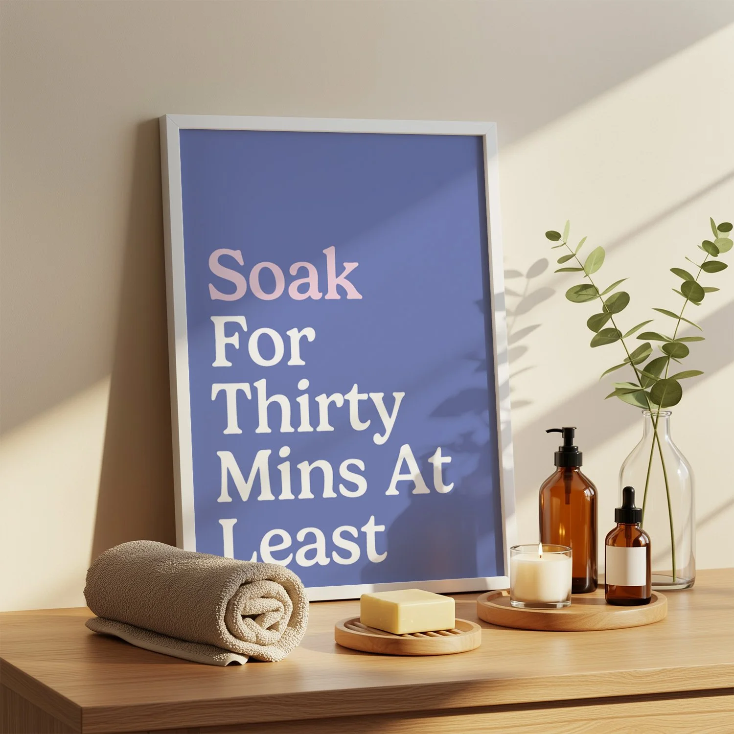 framed blue typography print on shelf with spa products either side and stacked towel