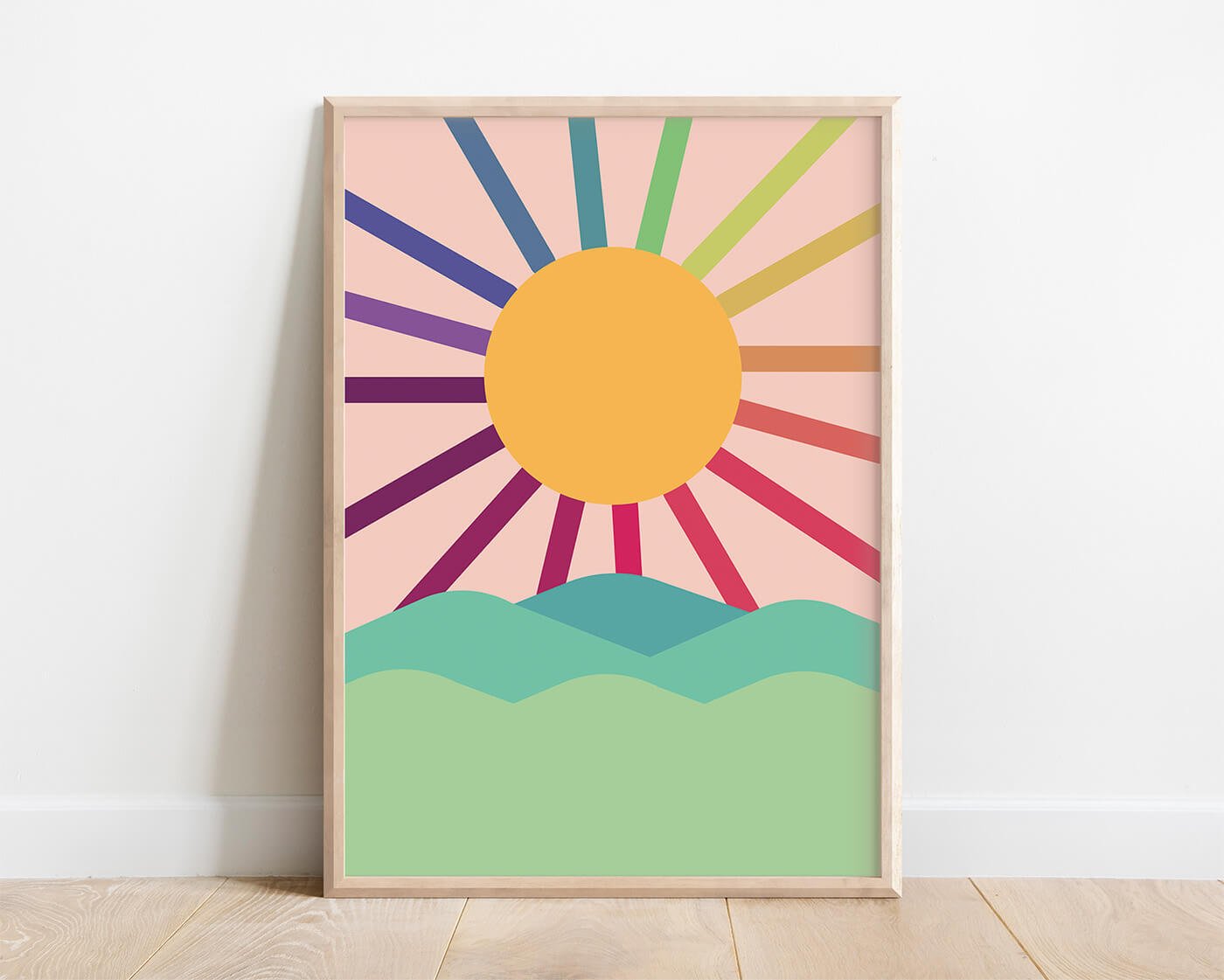 Peach coloured abstract sun print with green hills and blue sky displayed in wooden frame and leaning against modern interior wall