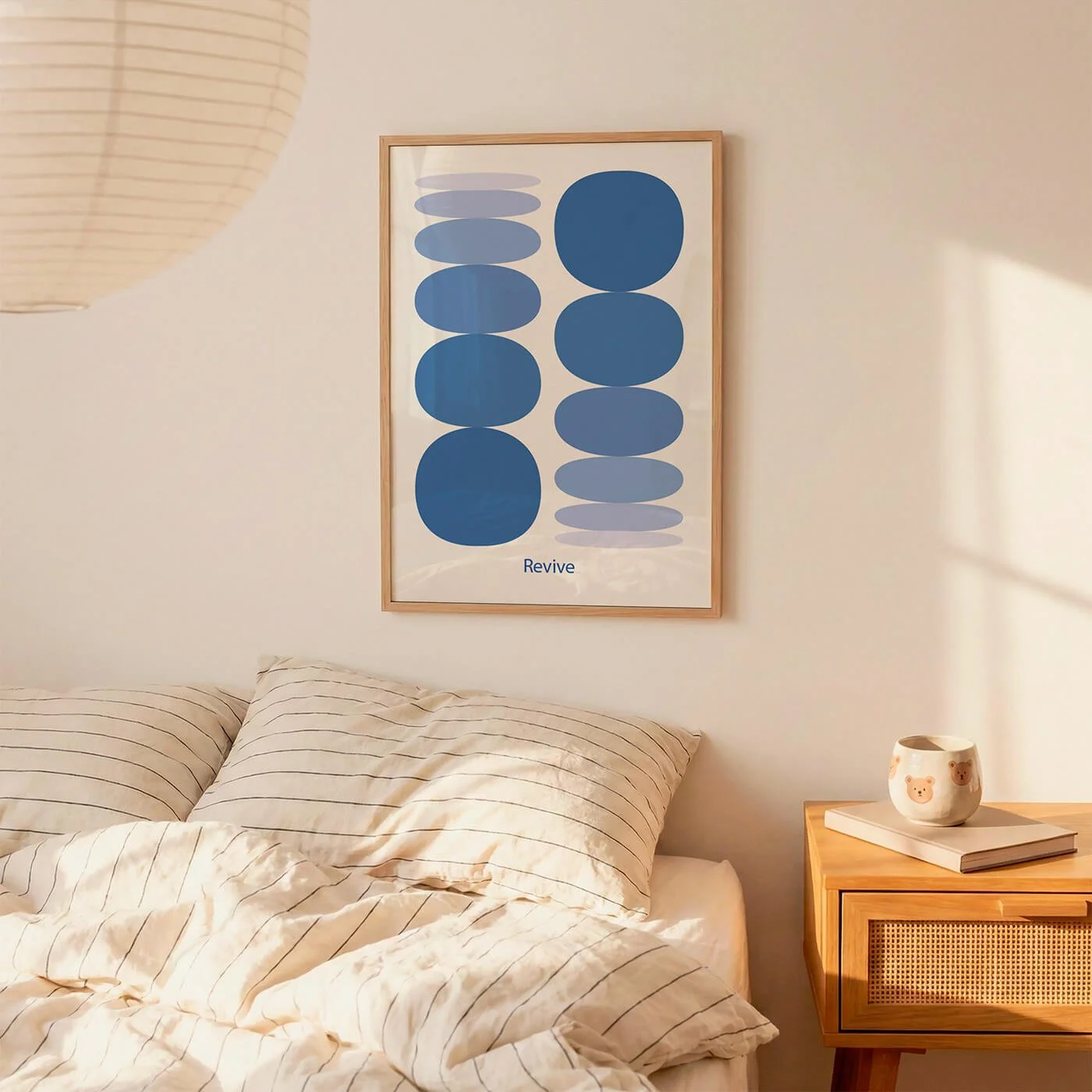 Framed blue abstract wellness art print over a bed next to a nightstand with a mug