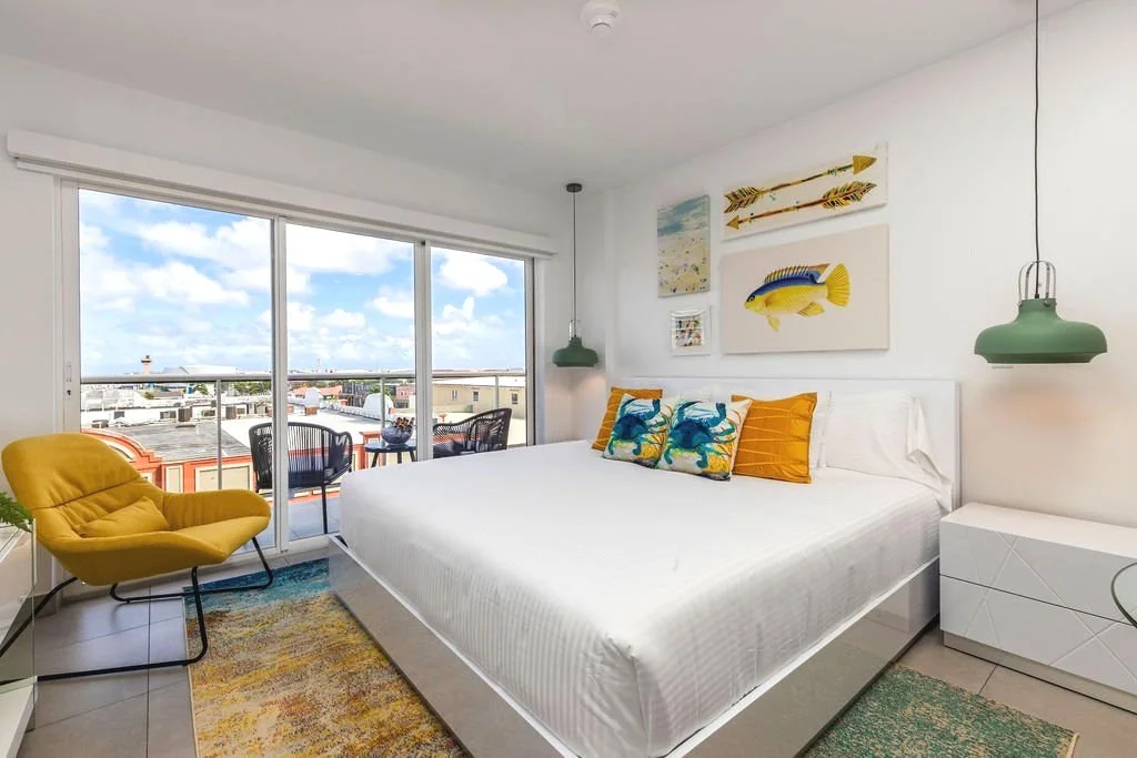 Светла спалня с ярка цветна декорация в реновирано AirBnb в Аруба по интериорен дизайн на Призма Студио.