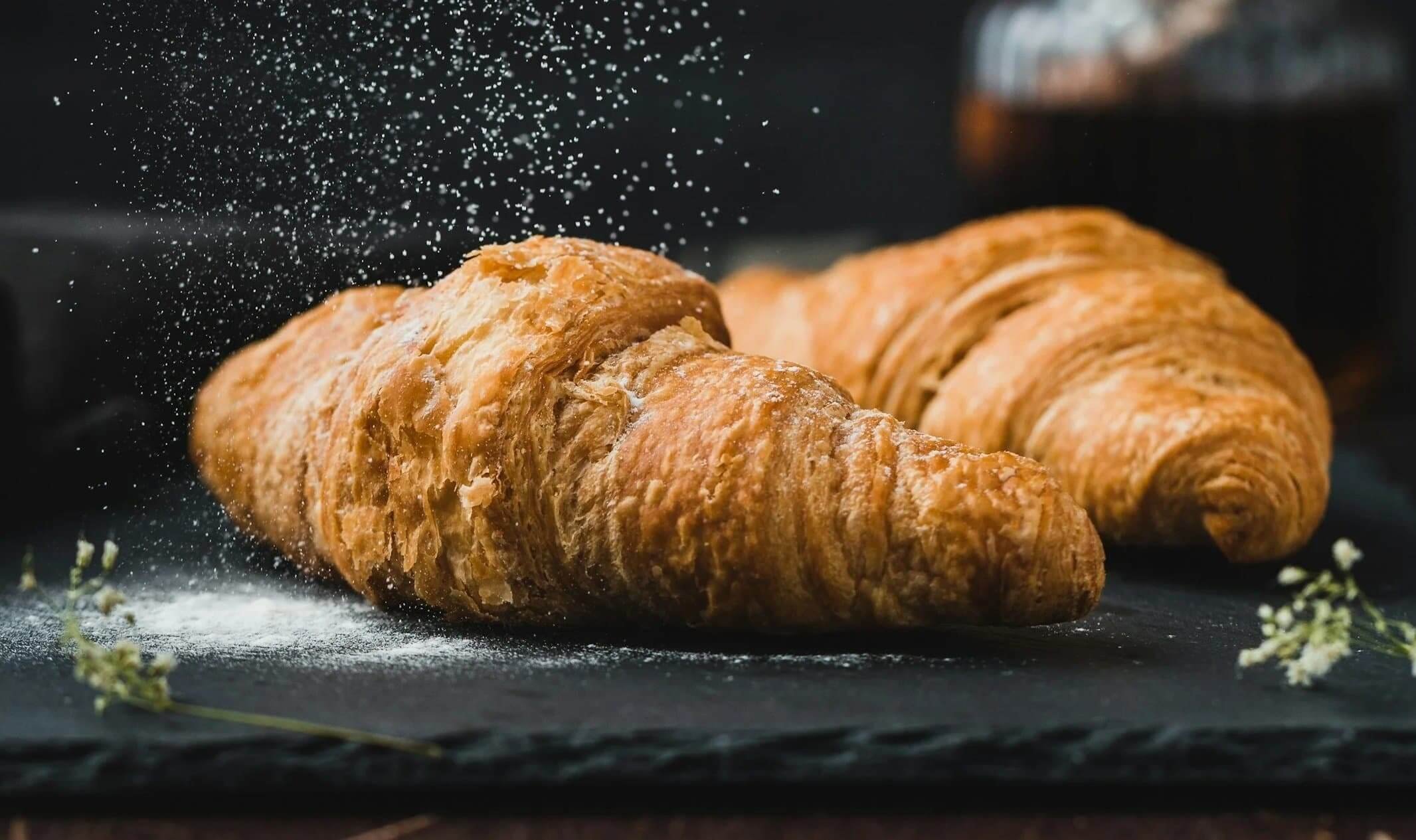 Croissants being dusted with icing sugar
