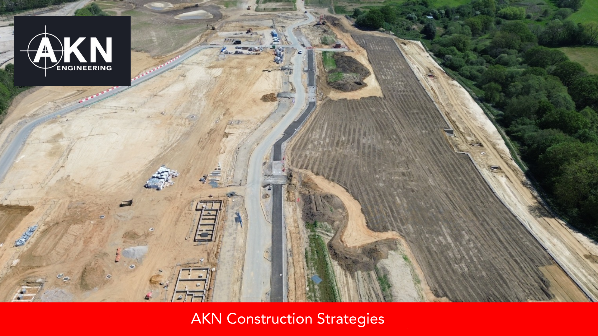 Aerial drone view of a large UK construction site showing a newly laid access road, set-out foundation trenches, earthworks, and haul routes across a groundworks development, captured by AKN Engineering.