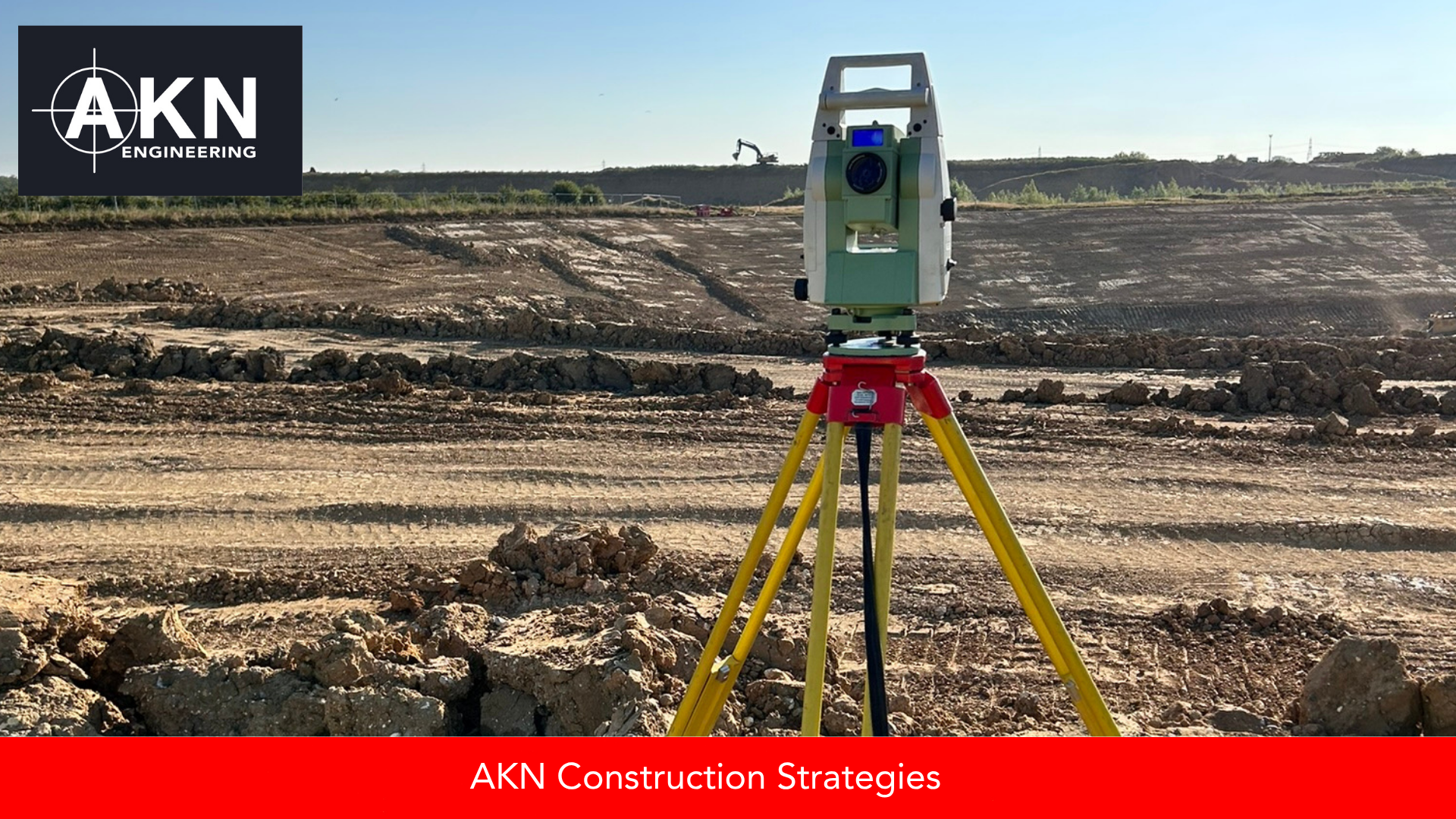 A total station on a yellow and red tripod in the foreground of a large-scale UK earthworks site, with extensive ground preparation, machinery and open horizon visible in the background, and the AKN Engineering logo overlay