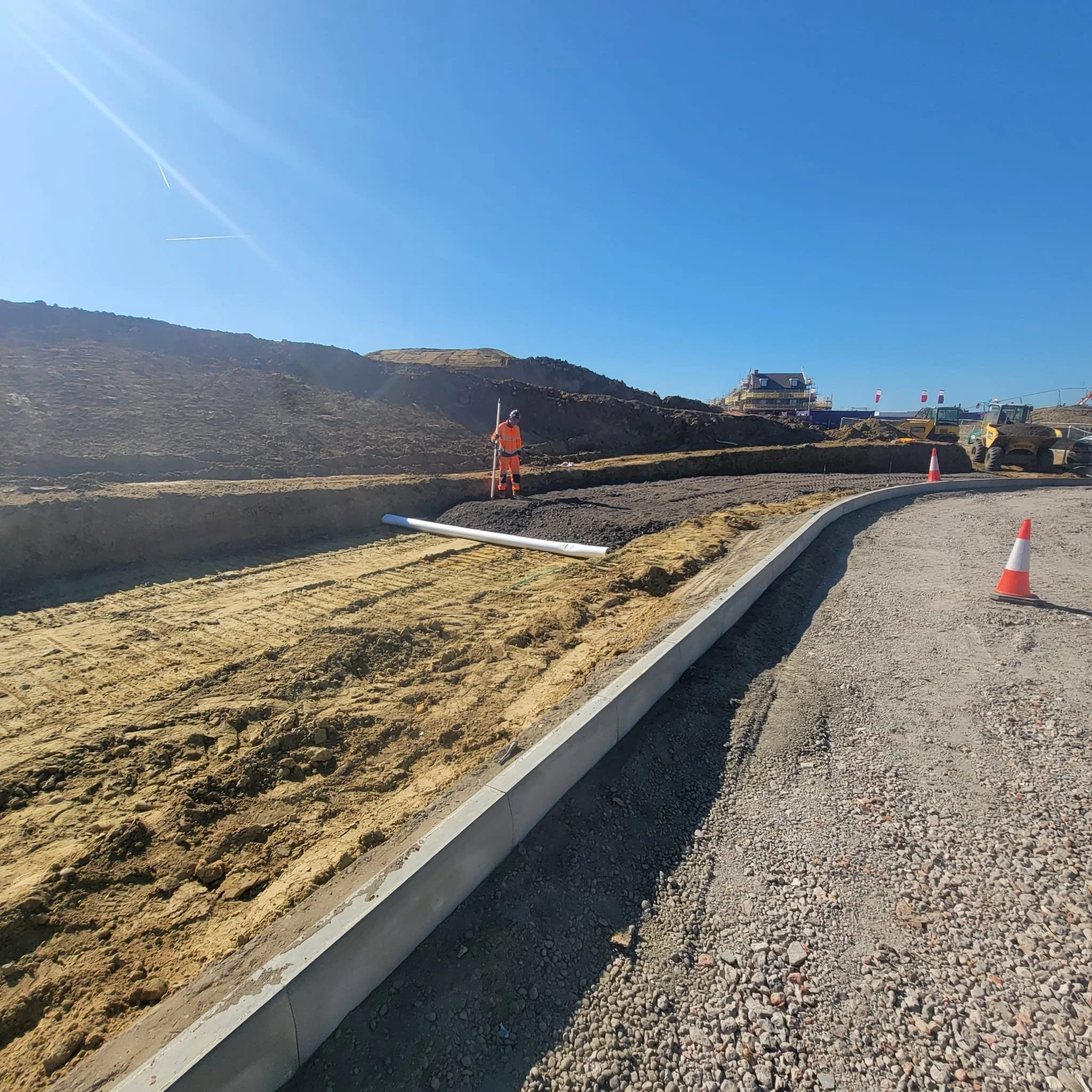 AKN Site Engineer in orange high Vis PPE, on a construction site setting out a path
