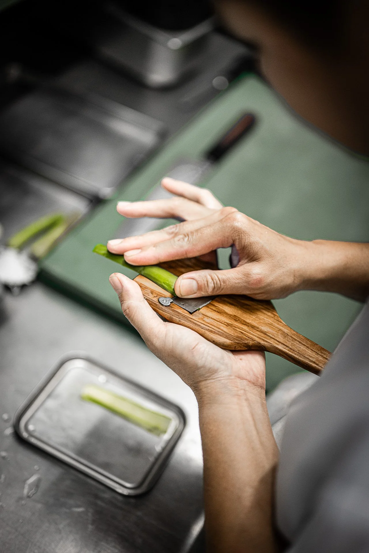 Une personne coupe un concombre sur une planche à découper en bois.