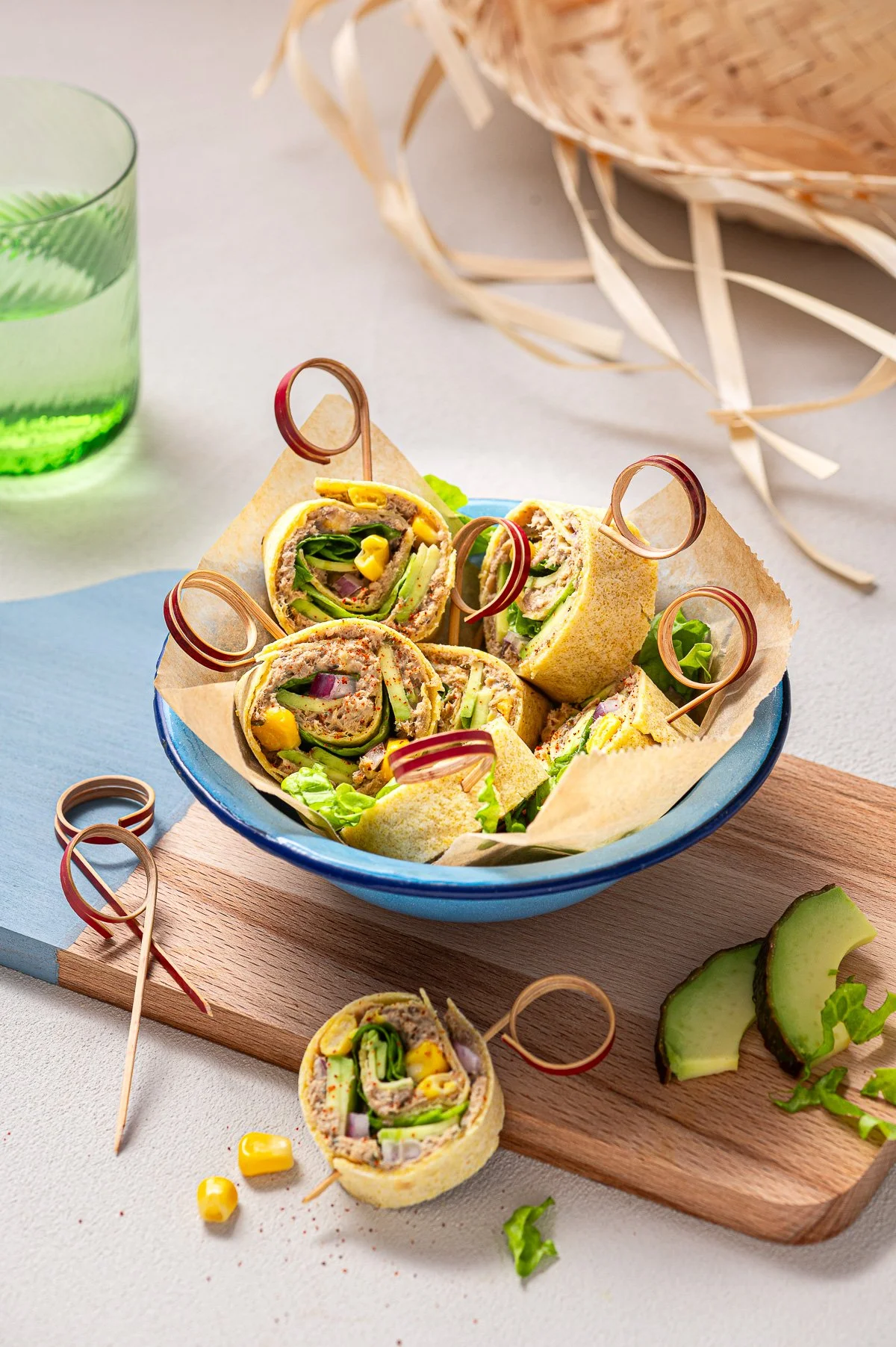 Assiette de sandwichs wraps farcis de légumes et de viande, garnis de rondelles de concombre et de cornichons, avec un verre d'eau verte à côté et des morceaux de concombre sur la surface.
