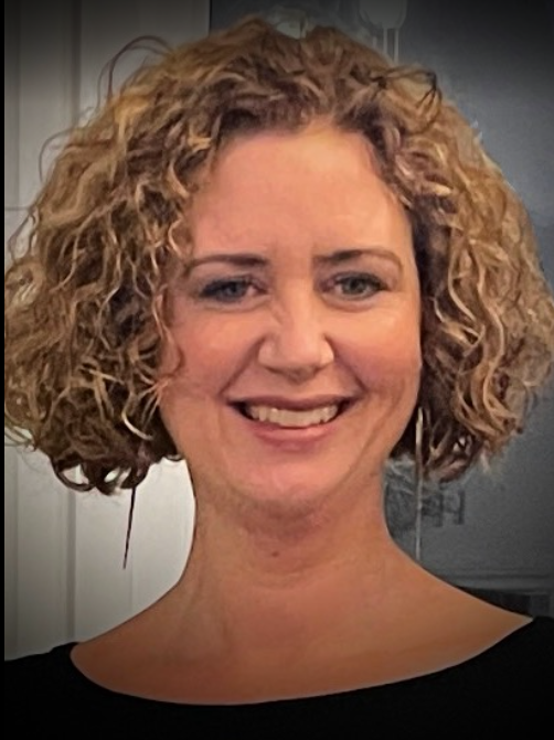 A woman with curly blonde hair smiling at the camera.