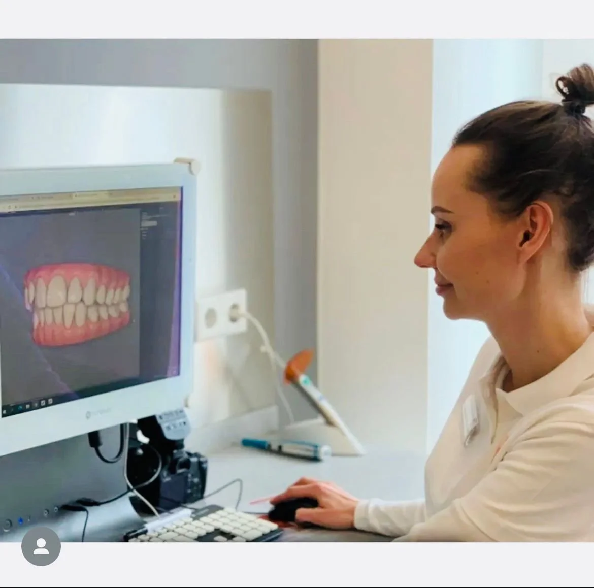 Eine Frau schaut auf einen Computermonitor, auf dem ein 3D-Modell von einem Gebiss und Zähnen zu sehen ist.