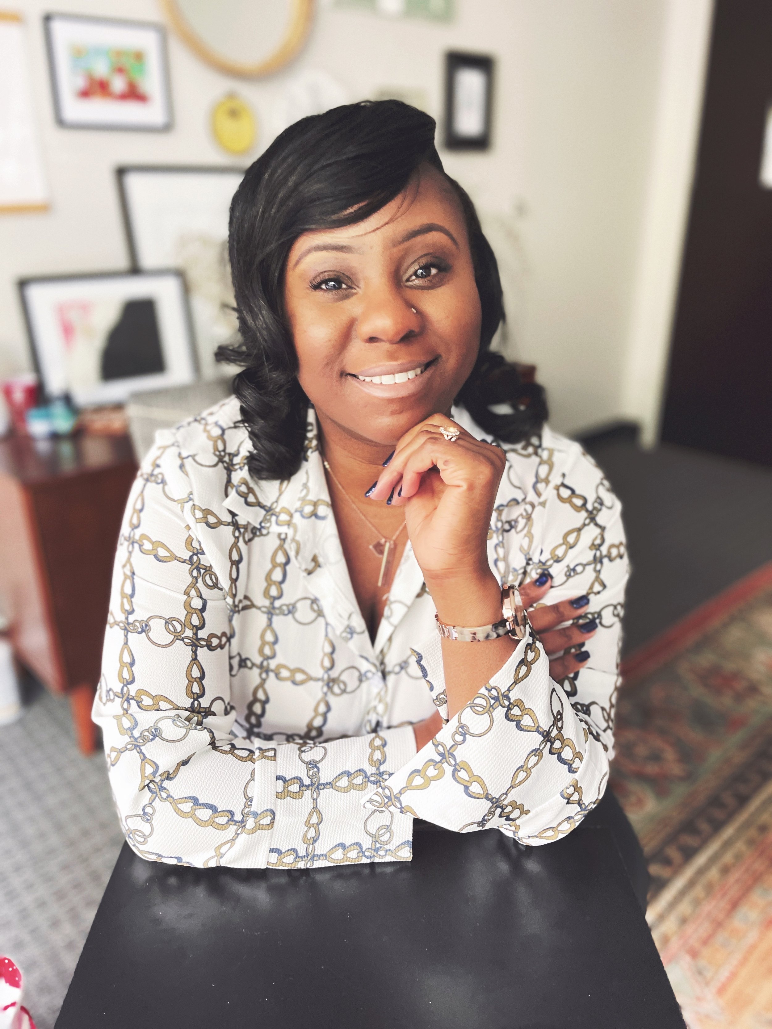 Smiling person in patterned shirt sitting at a desk