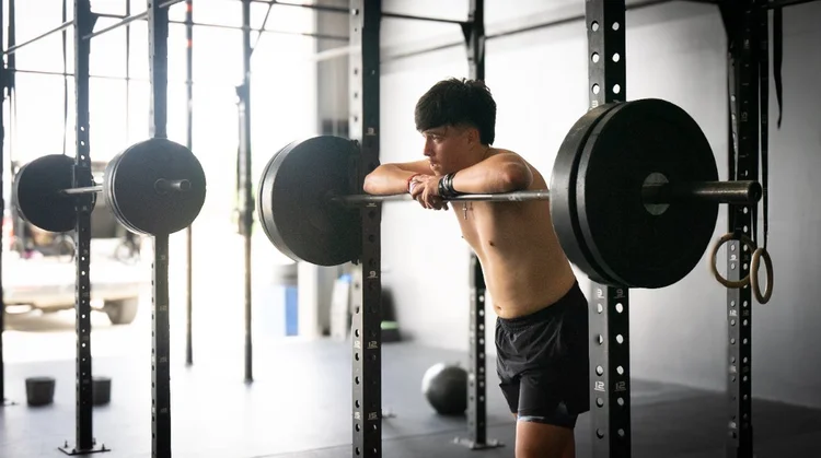 Teen athlete resting on a barbell during youth athlete training in New Braunfels