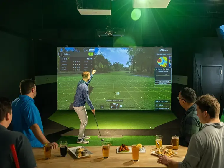 Men play indoor golf in a simulator bay