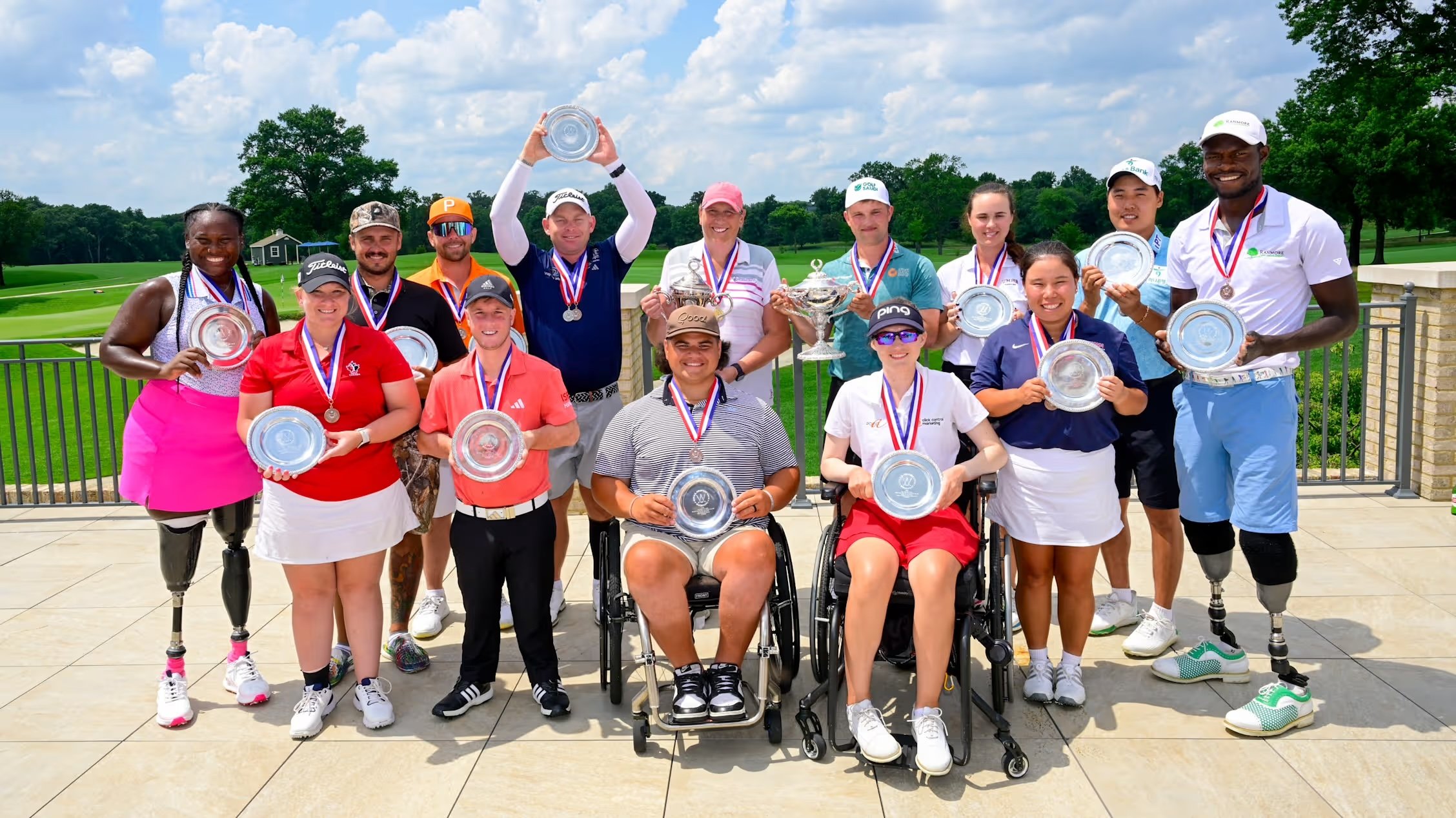 A golfer with prosthetic legs swings a golf club on the course while a golf cart is nearby, surrounded by green trees and grass.