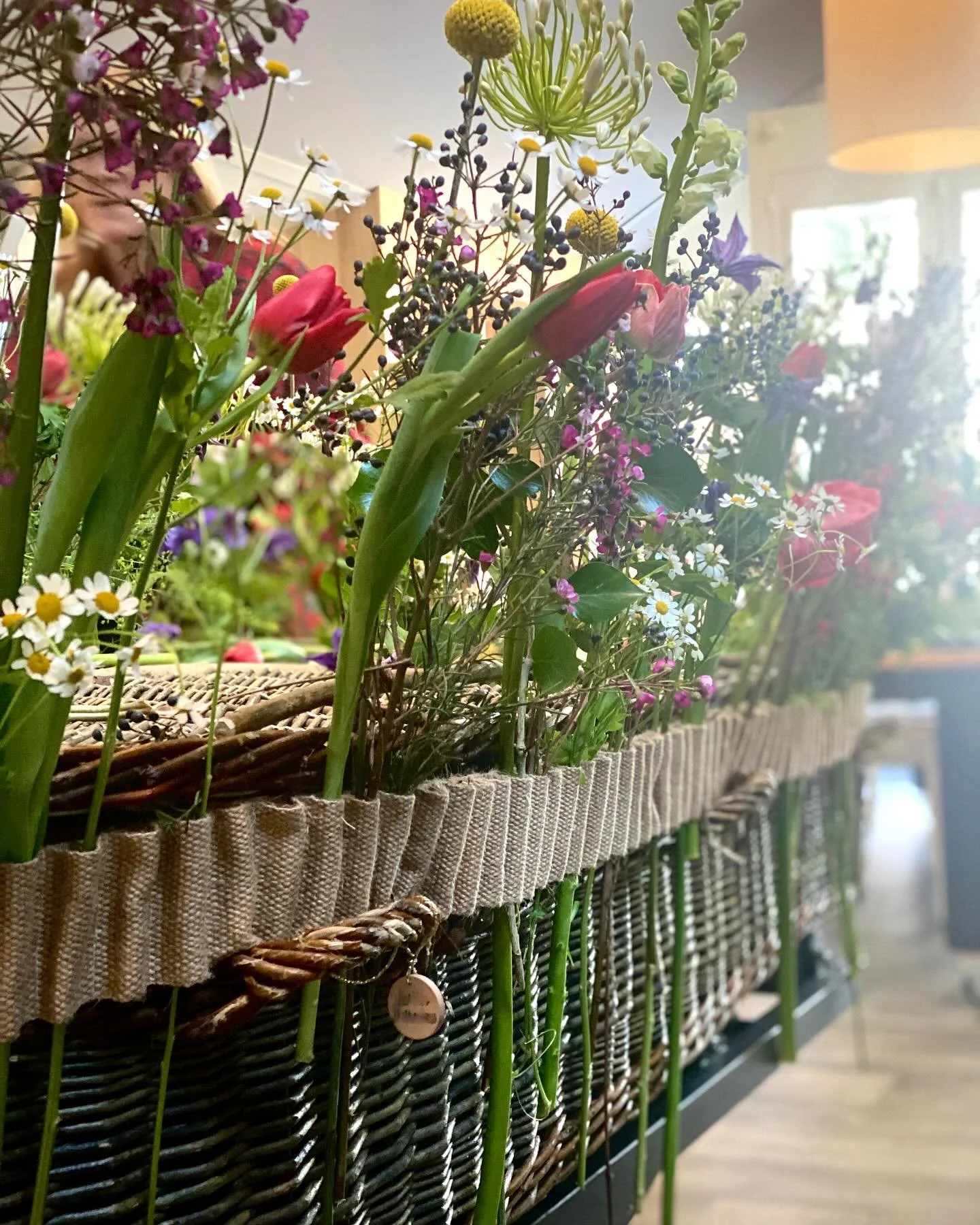 De met zorg gevlochten wilgentenen mand van De Mythe, omhuld door de verfijnde jute bloemenband &ndash; een laatste liefdevolle omarming, zoals zo mooi verwoord staat op hun website www.bloemenband.nl.
Voor de uitvaart van hun geliefde vriendin kozen