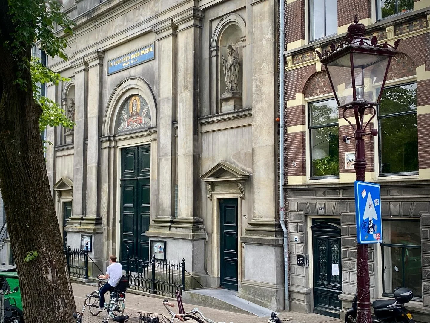 Deze ochtend, in alle vroegte, sta ik stil voor de prachtige kerk De Duif in Amsterdam.
 Een kort moment van rust, terwijl de stad langzaam ontwaakt en fietsers in hoog tempo aan mij voorbijgaan.

Voor anderen staat de tijd vandaag even stil. Zij nem