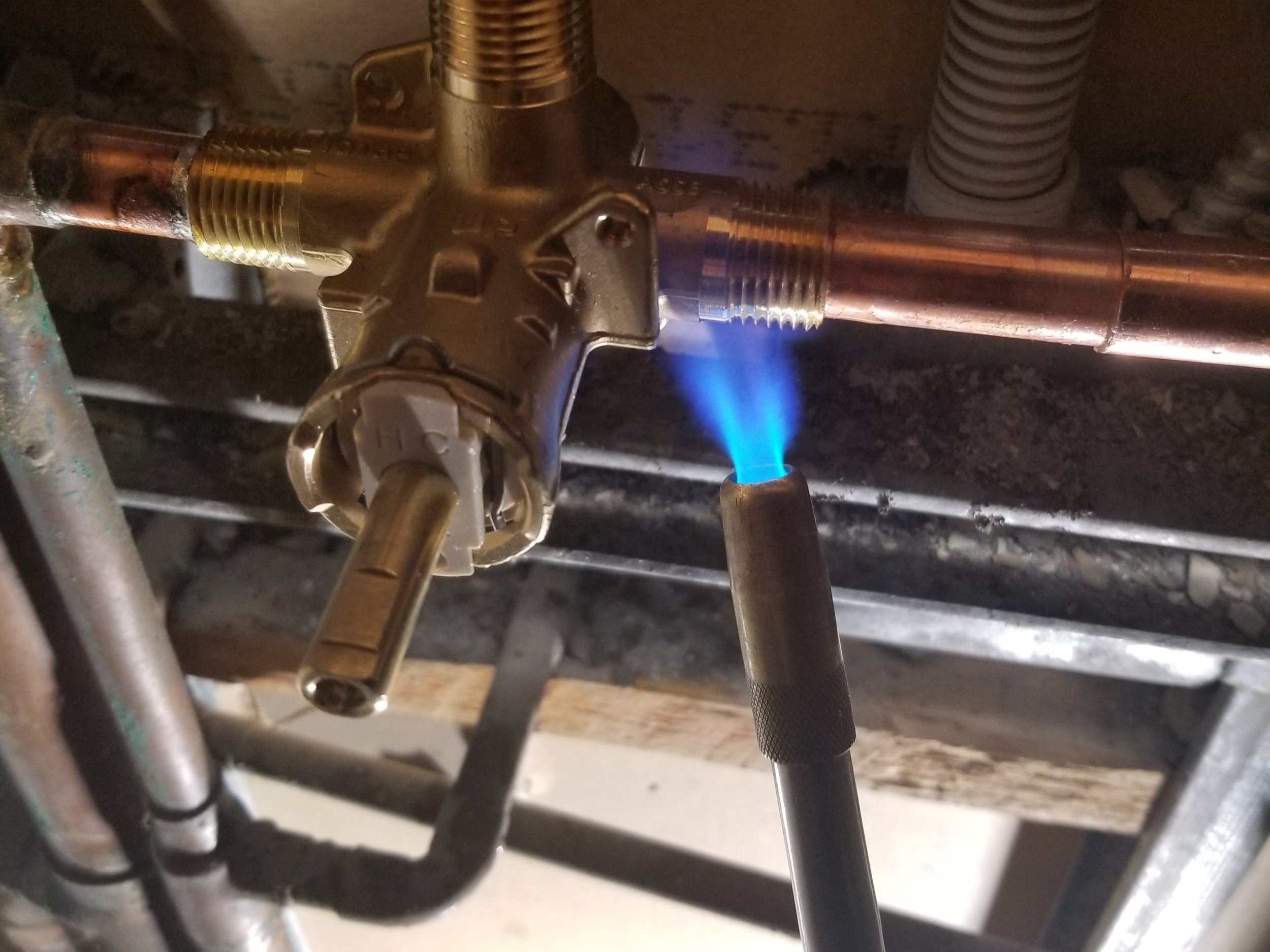 Close-up of plumbing fittings and a blowtorch used for soldering copper pipes.