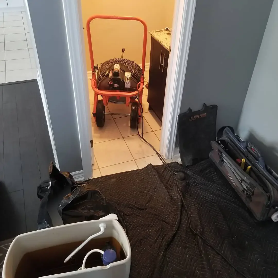 Drain snake equipment clearing a clogged residential drain during professional drain cleaning service.