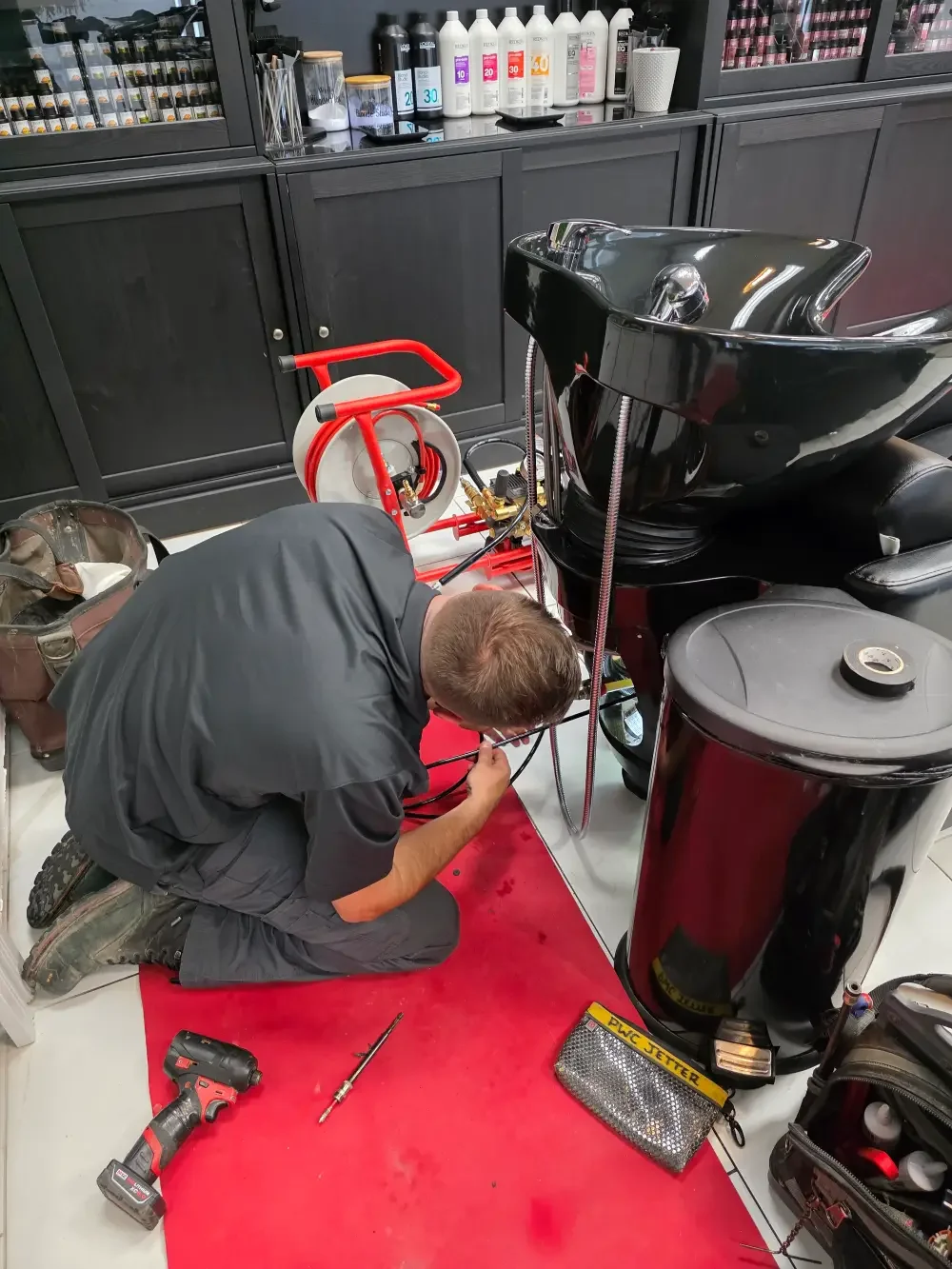 Professional plumber using hydro jetting equipment to clear a clogged salon drain in Springwater, Ontario.