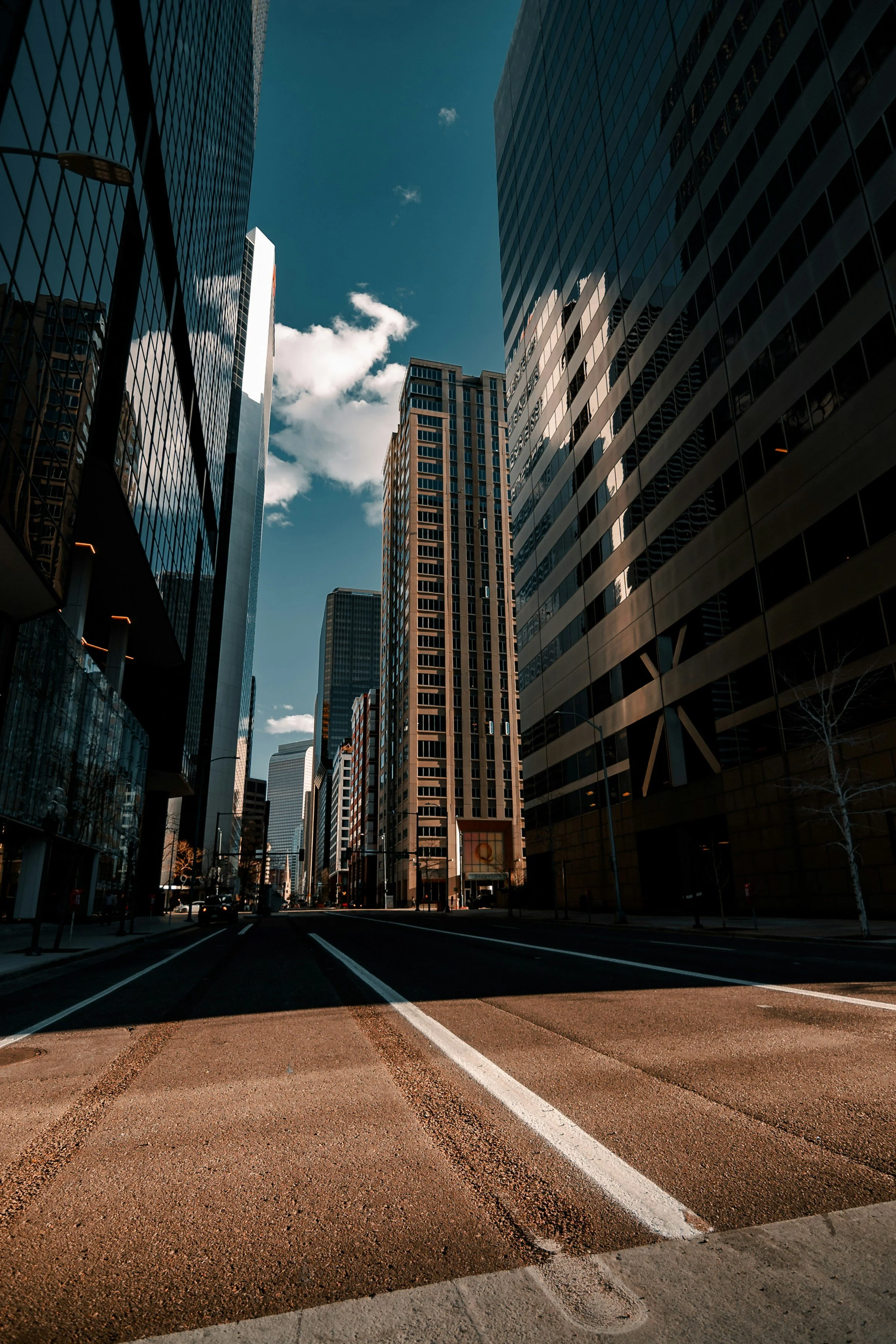Clear city street with buildings on either side under a blue sky.