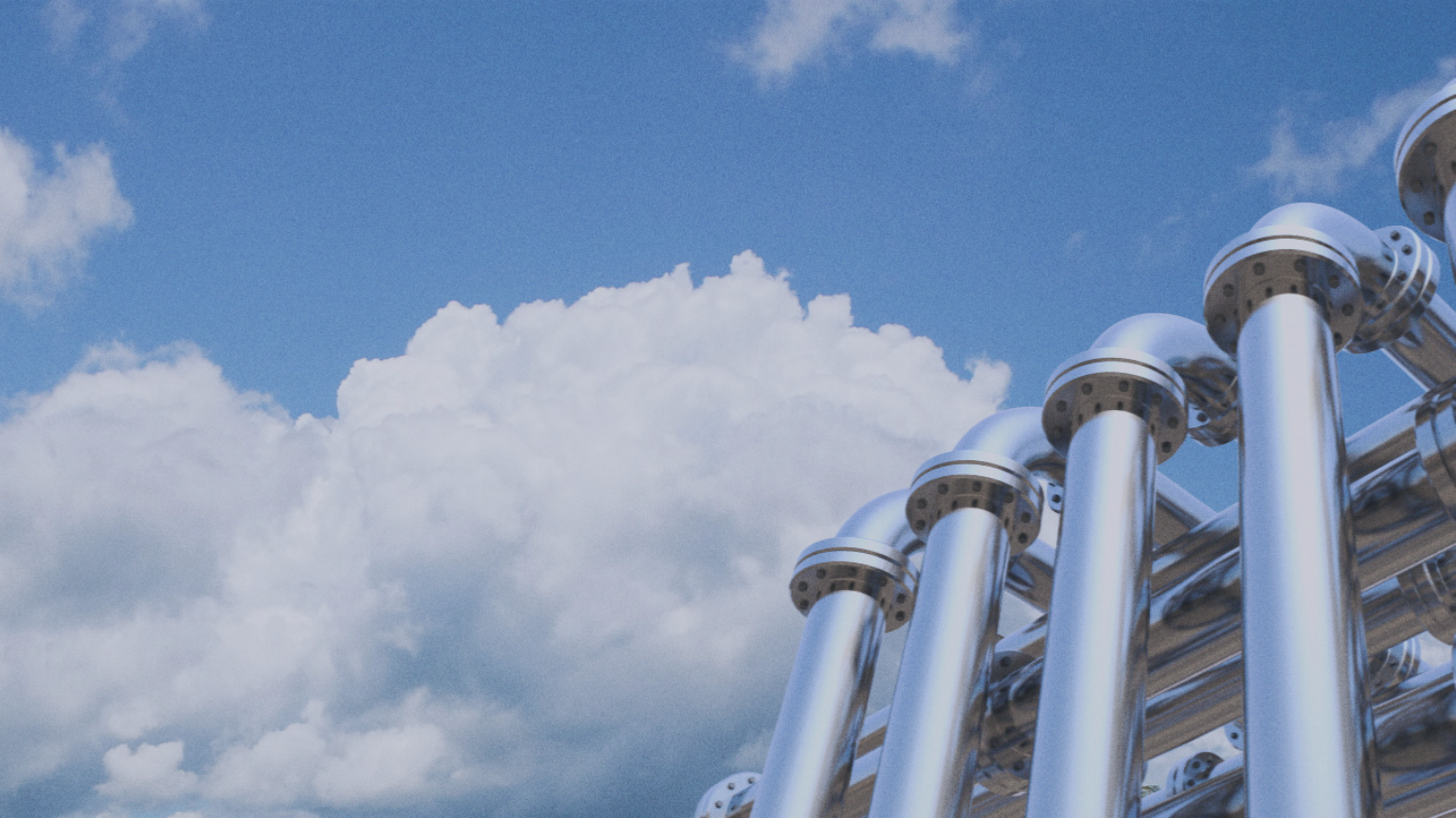 A close-up of a row of shiny metallic pipes with a cloudy blue sky in the background.