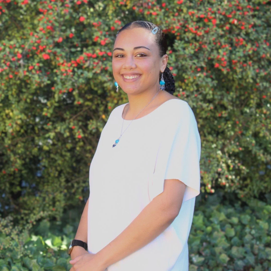 A smiling woman with a white shirt, and blue jewelry