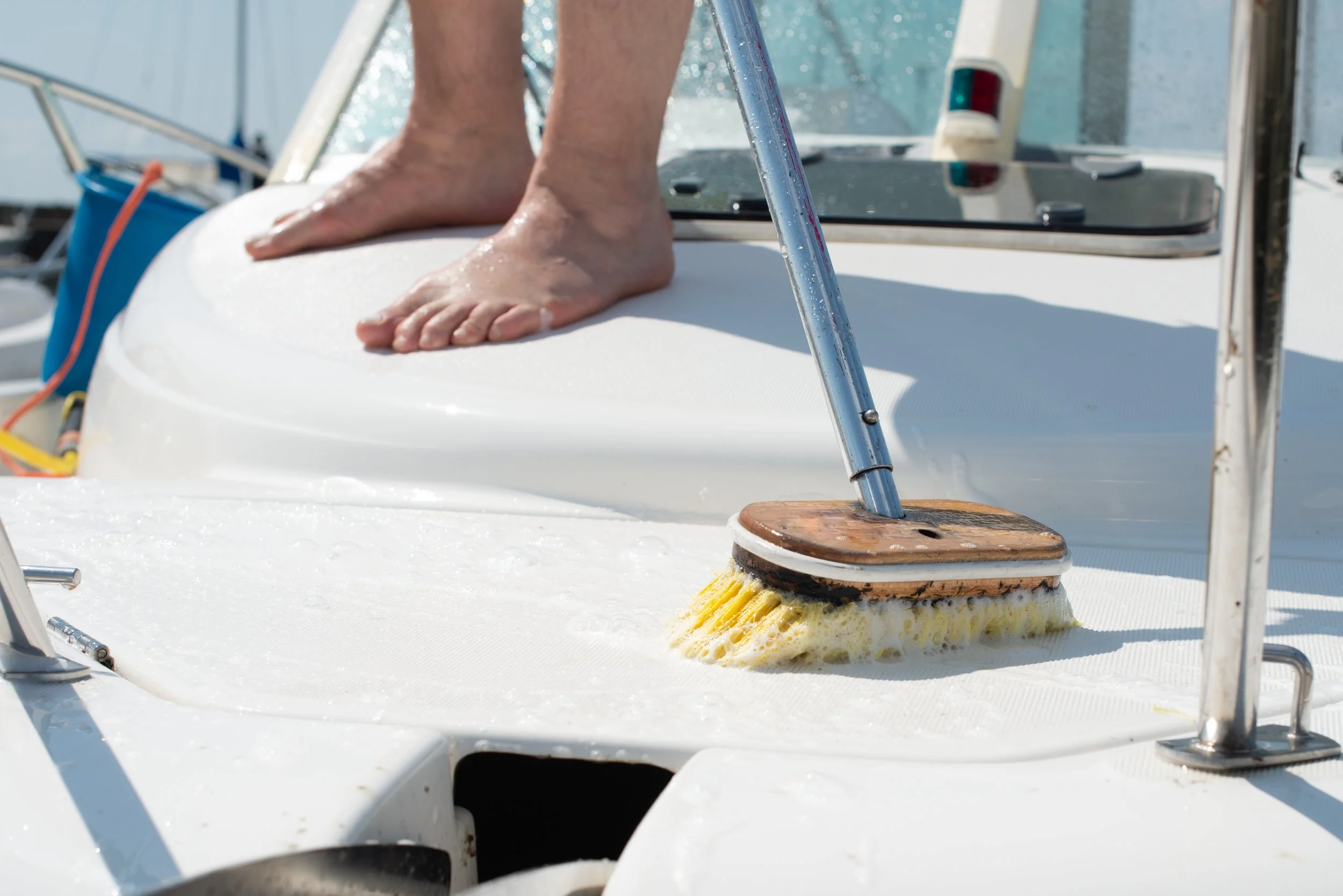 Person cleaning a yacht deck with a brush.