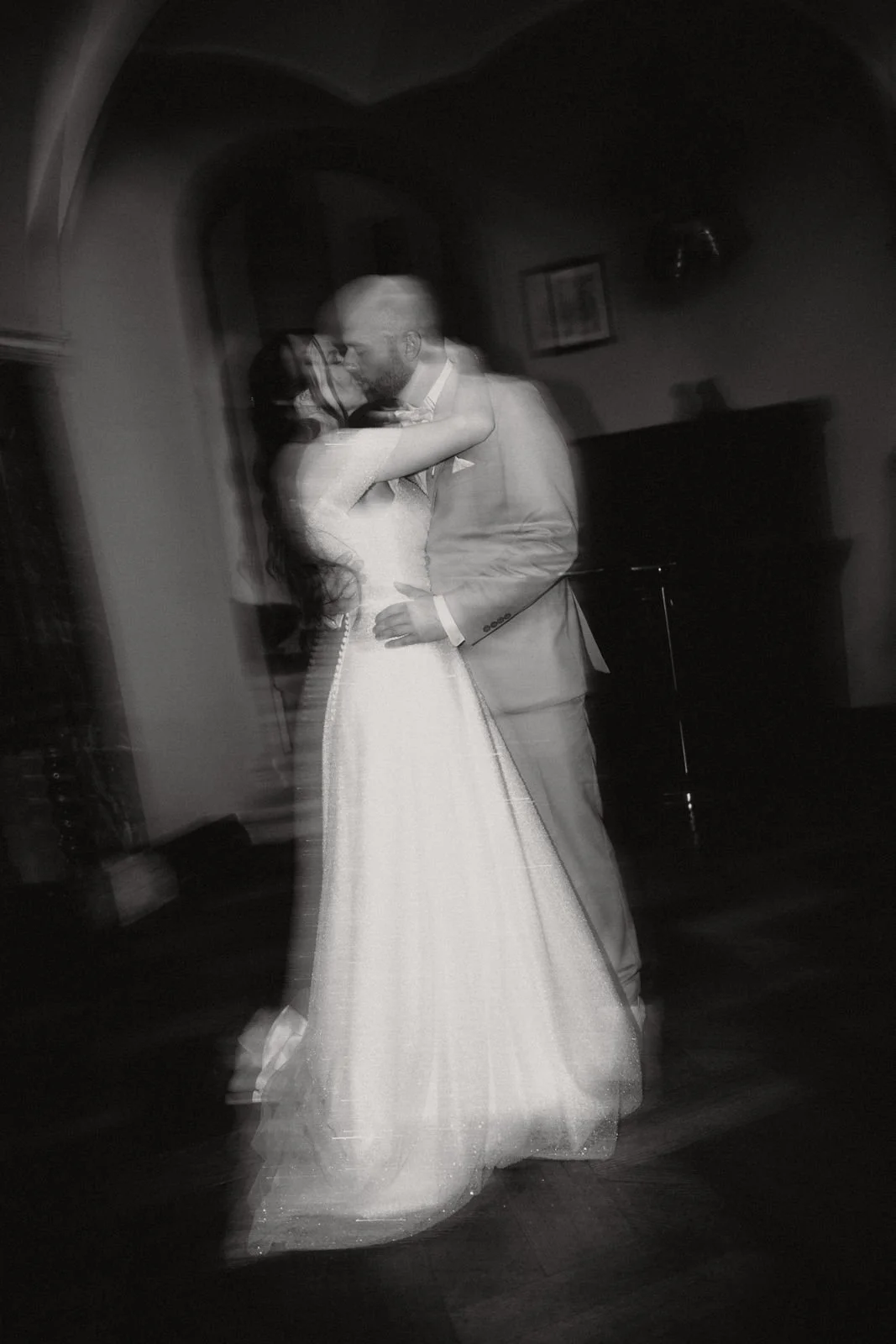 Ein schwarz-weiß Foto eines Paares beim Tanzen, vermutlich bei einer Hochzeit, mit leicht verschwommenem Eindruck.