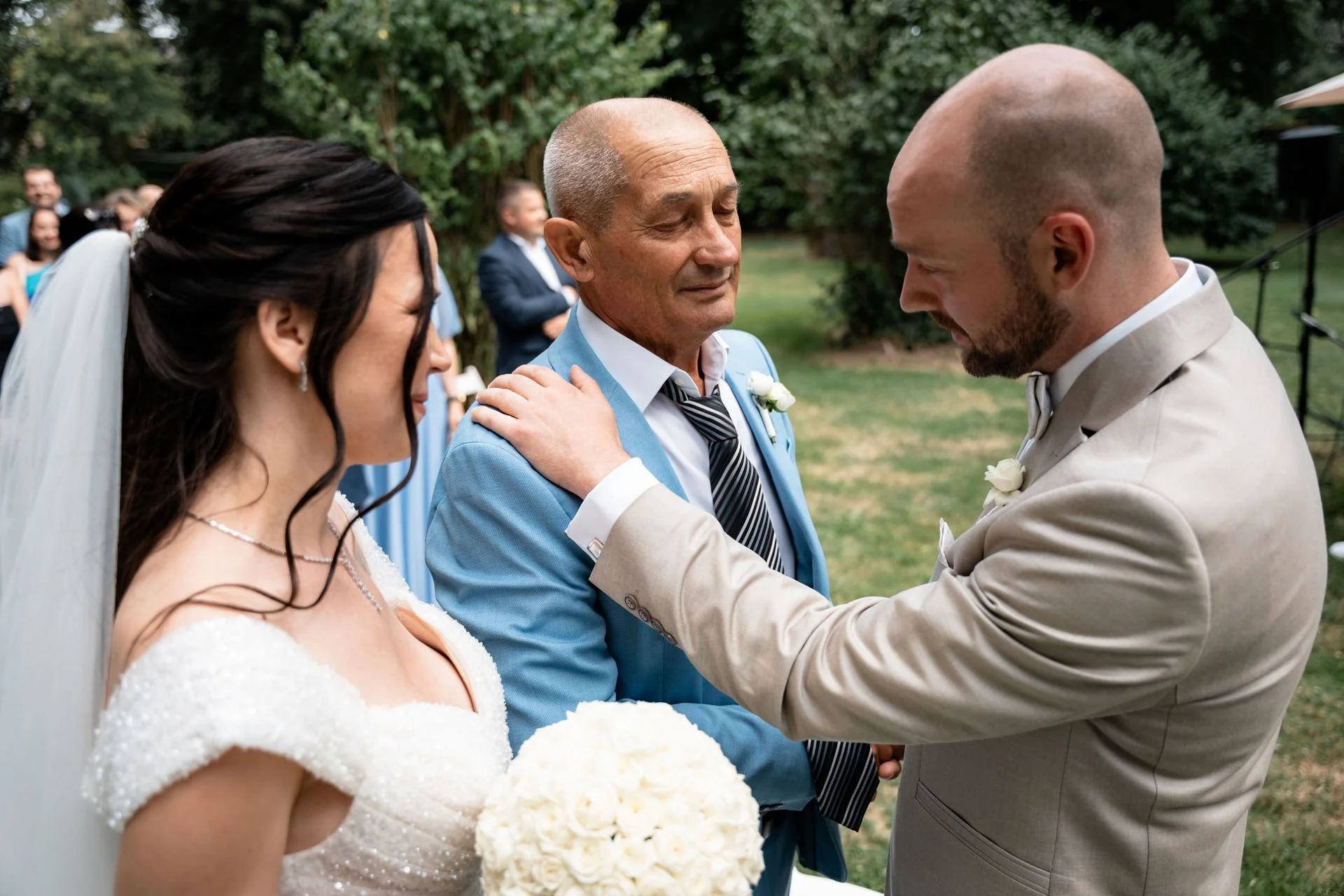 Ein Hochzeitspaar verabschiedet sich emotional bei ihrer Trauung im Freien, umgeben von Freunden und Familie.