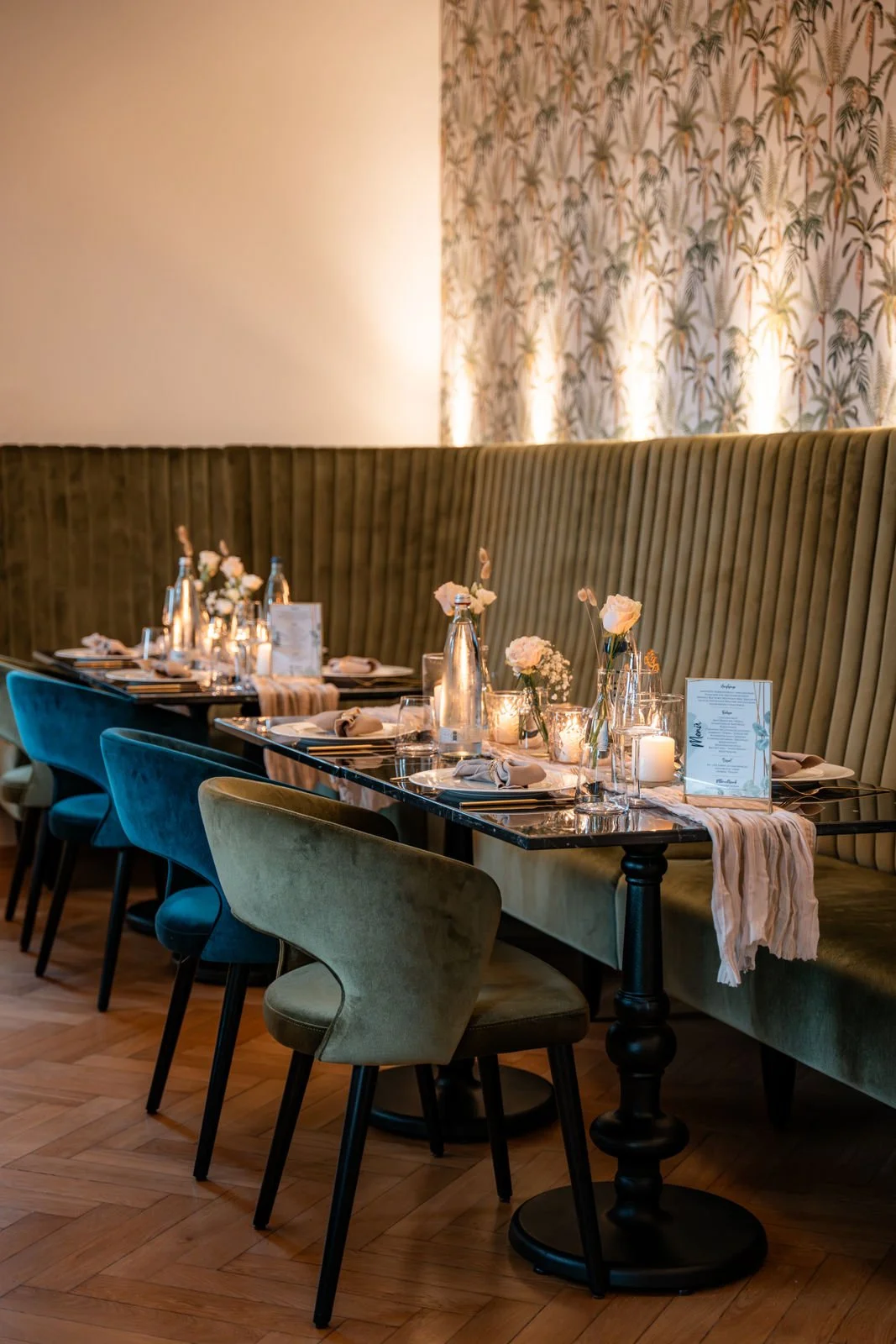 Gemütlich gedeckter Esstisch in einem eleganten Restaurant mit Kerzen, Blumen und Menu-Karten, umgeben von bequemen Stühlen.