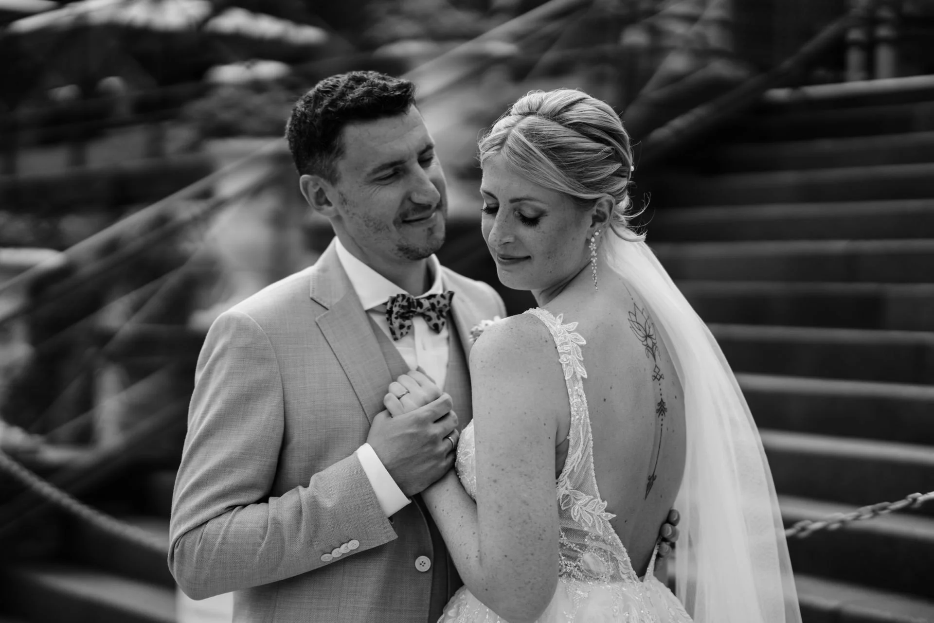 Braut und Bräutigam beim Jawort, umarmend und lächelnd, auf einer Holztreppe im Freien, schwarz-weiß