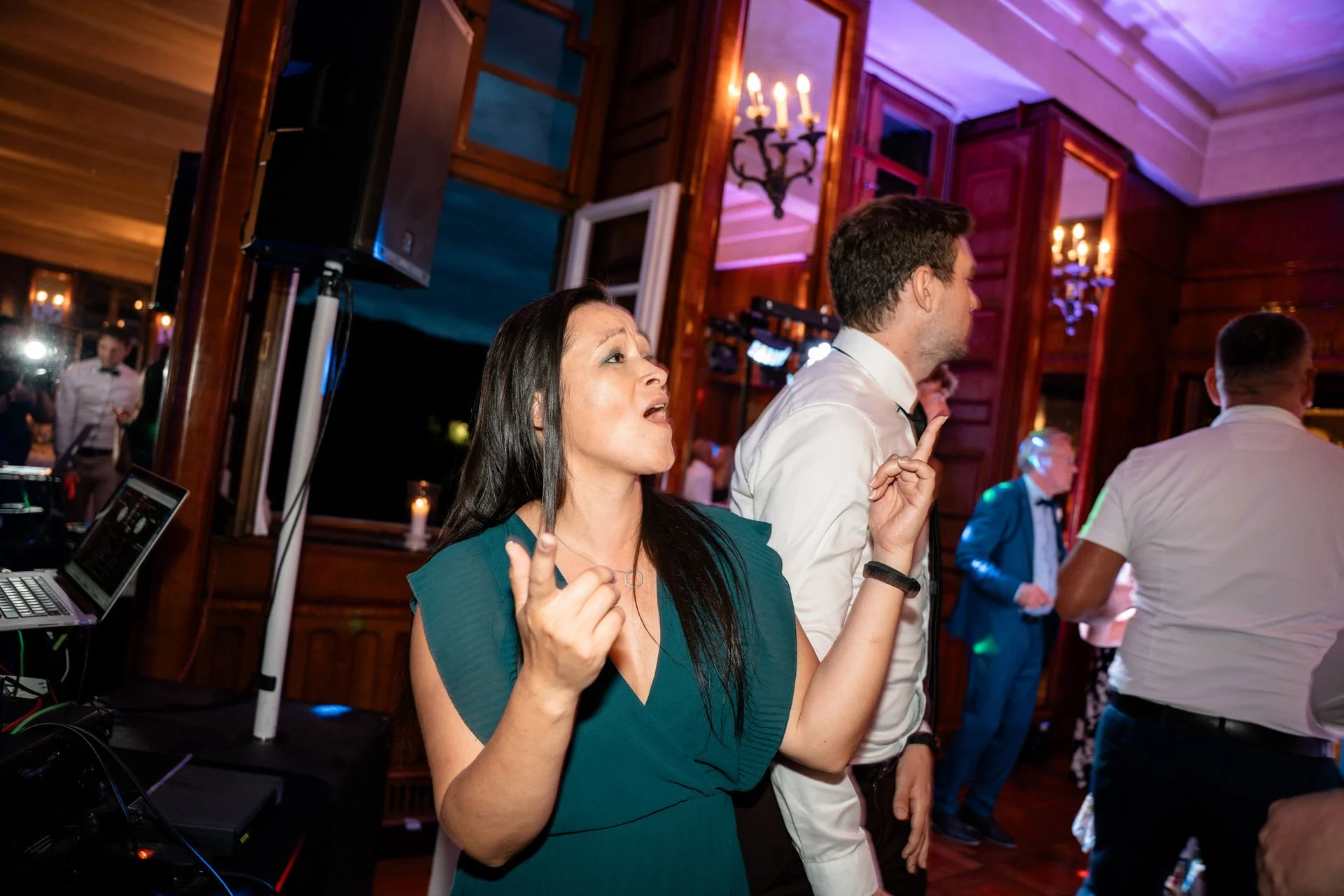 Eine Gruppe von Leuten tanzt bei einer Party im Holzhaus mit Kerzen und bunten Lichtern.